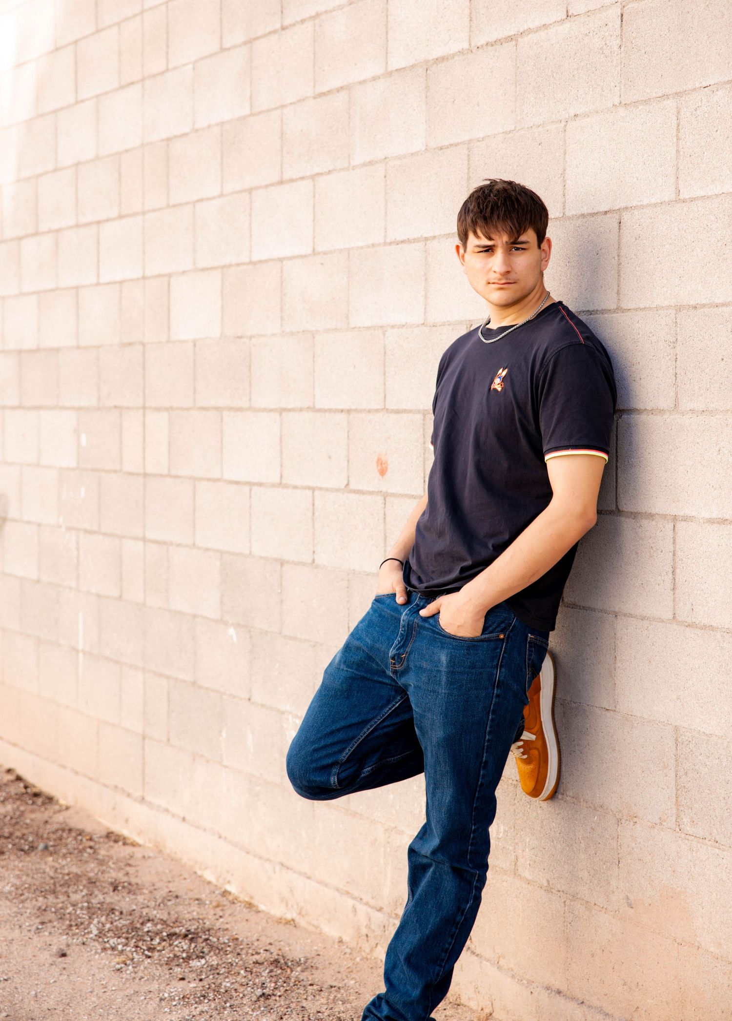Person in black shirt and jeans leans against white wall in series of contemplative poses.