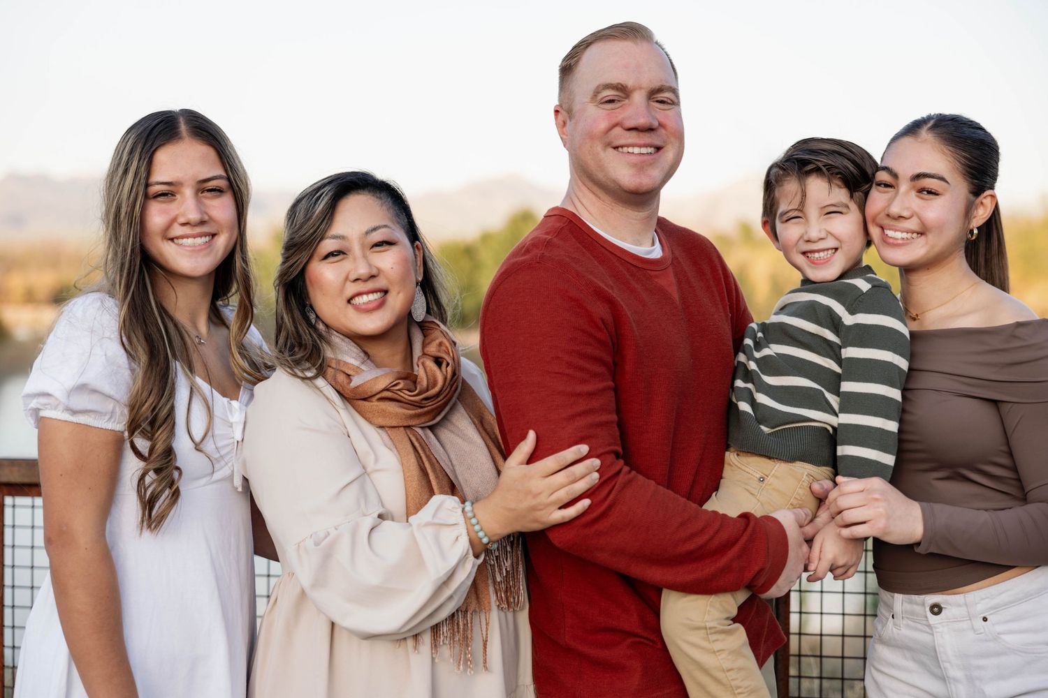A group smiles together while posing for casual outdoor portraits in coordinated casual attire.