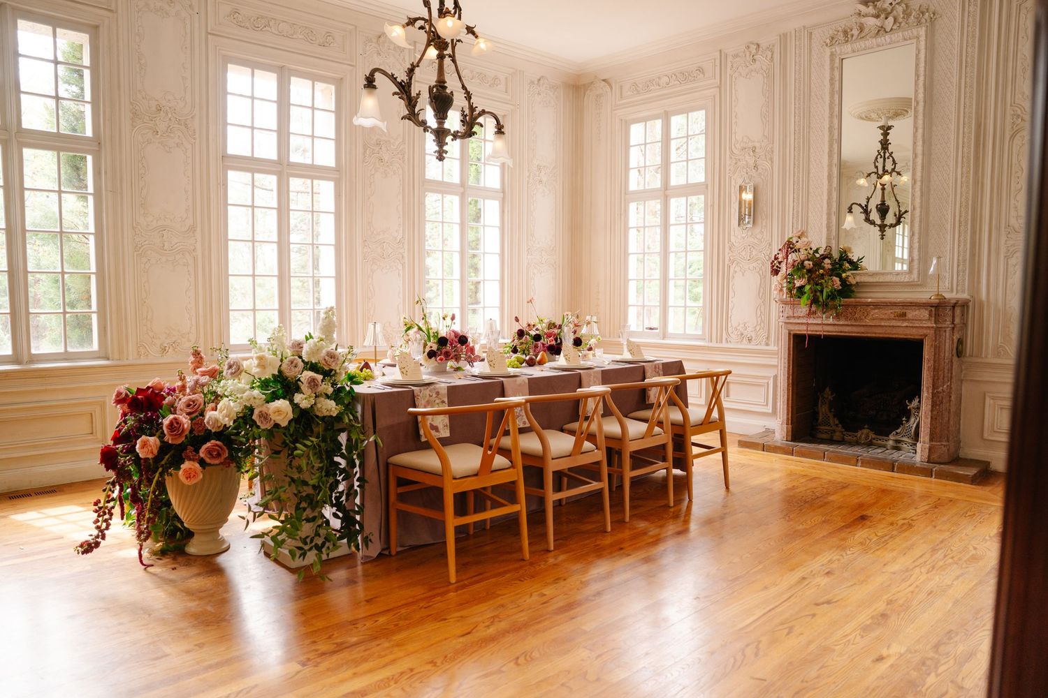 Bright sunlit ballroom with hardwood floors, chandeliers and large windows creates an elegant event space.
