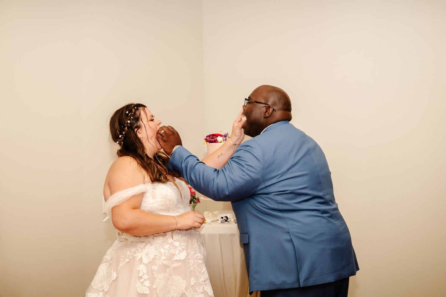 Newlyweds playfully feed each other cake during their wedding reception.