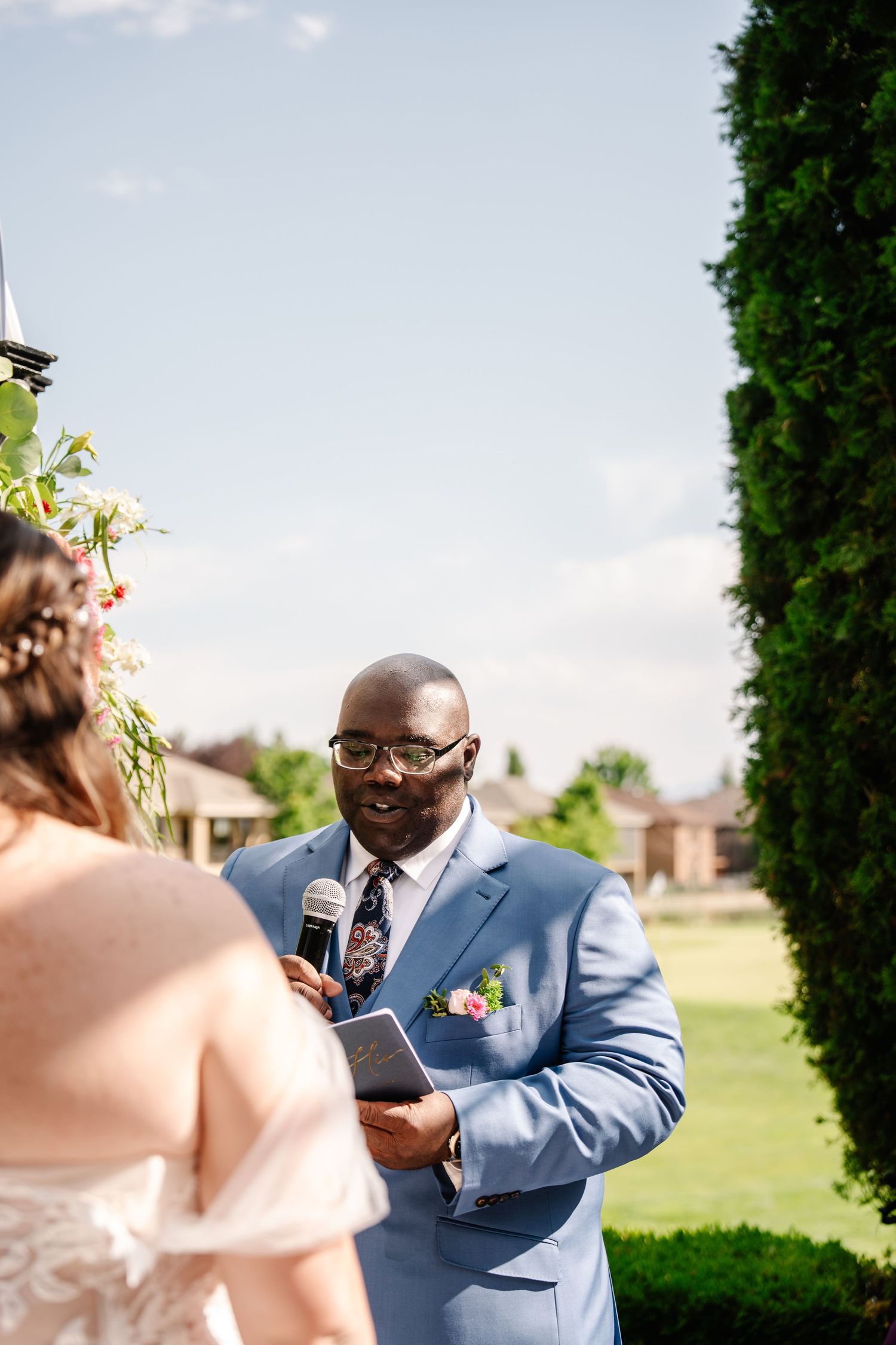 Wedding ceremony taking place on a lush green lawn with vows being exchanged.
