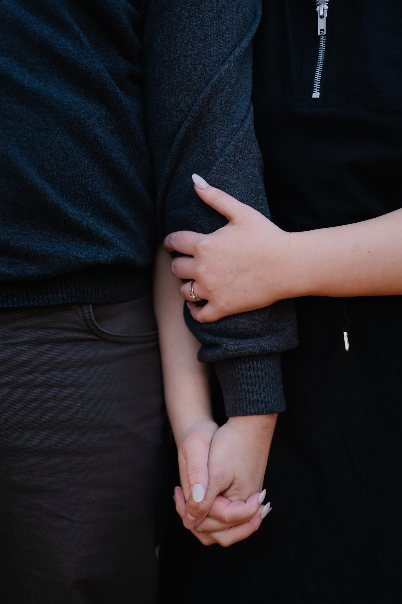 Close-up sequence showing two hands coming together and intertwining fingers against a dark background.