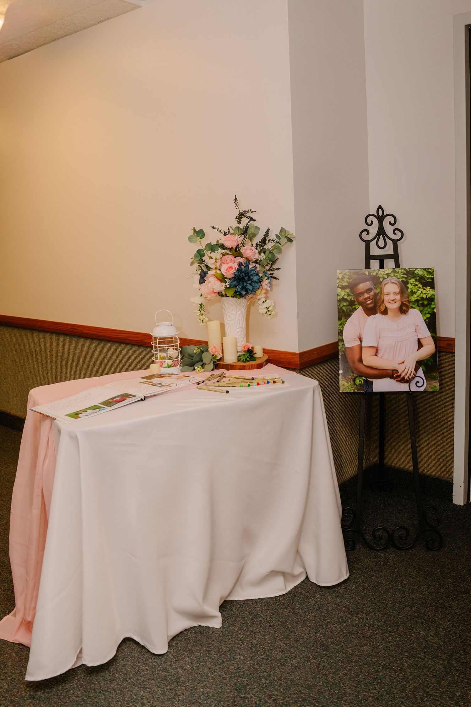 Reception tables with white tablecloths decorated with floral centerpieces and candles.