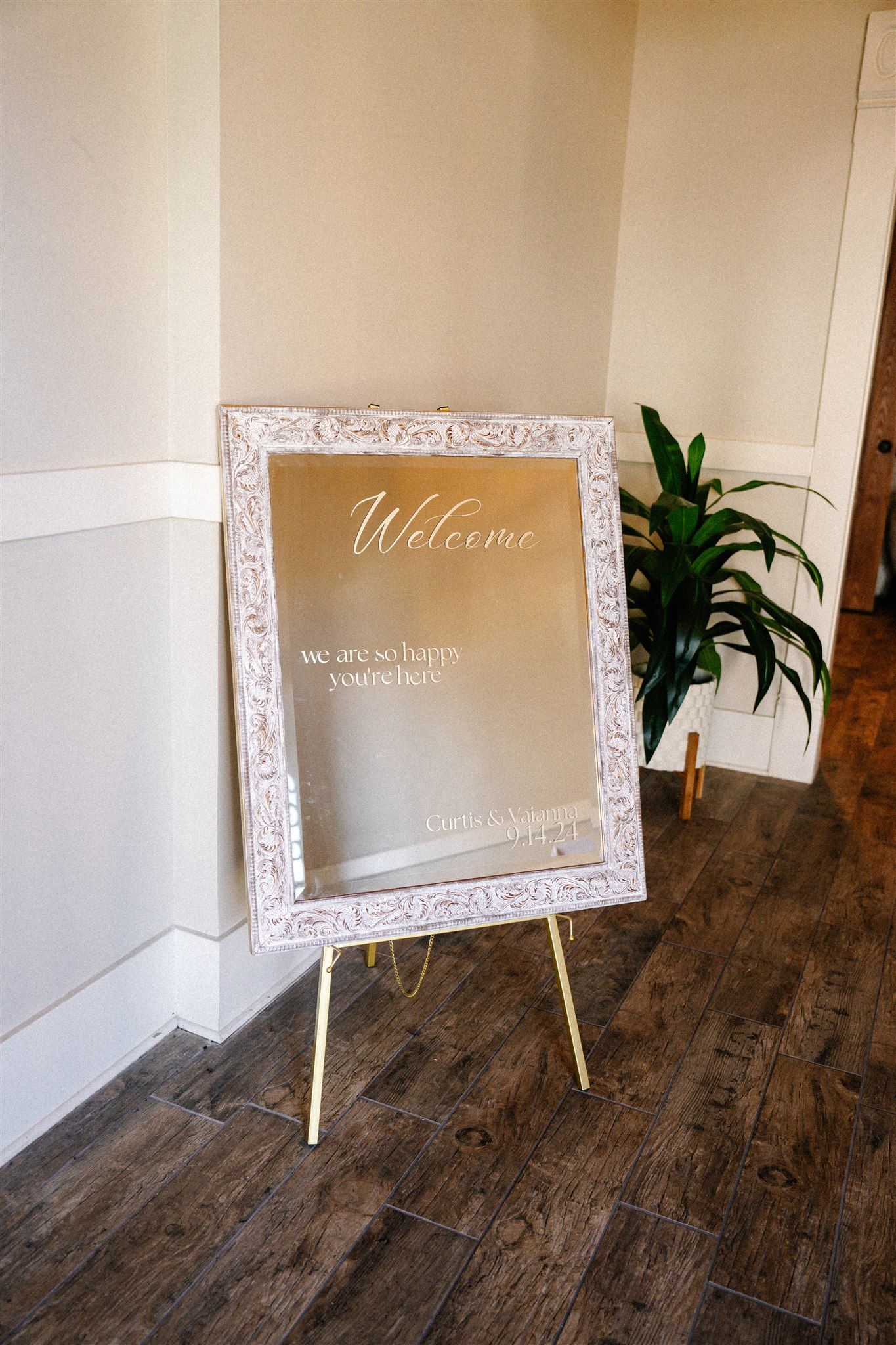 Ornate white welcome sign frame displayed against wooden floor.
