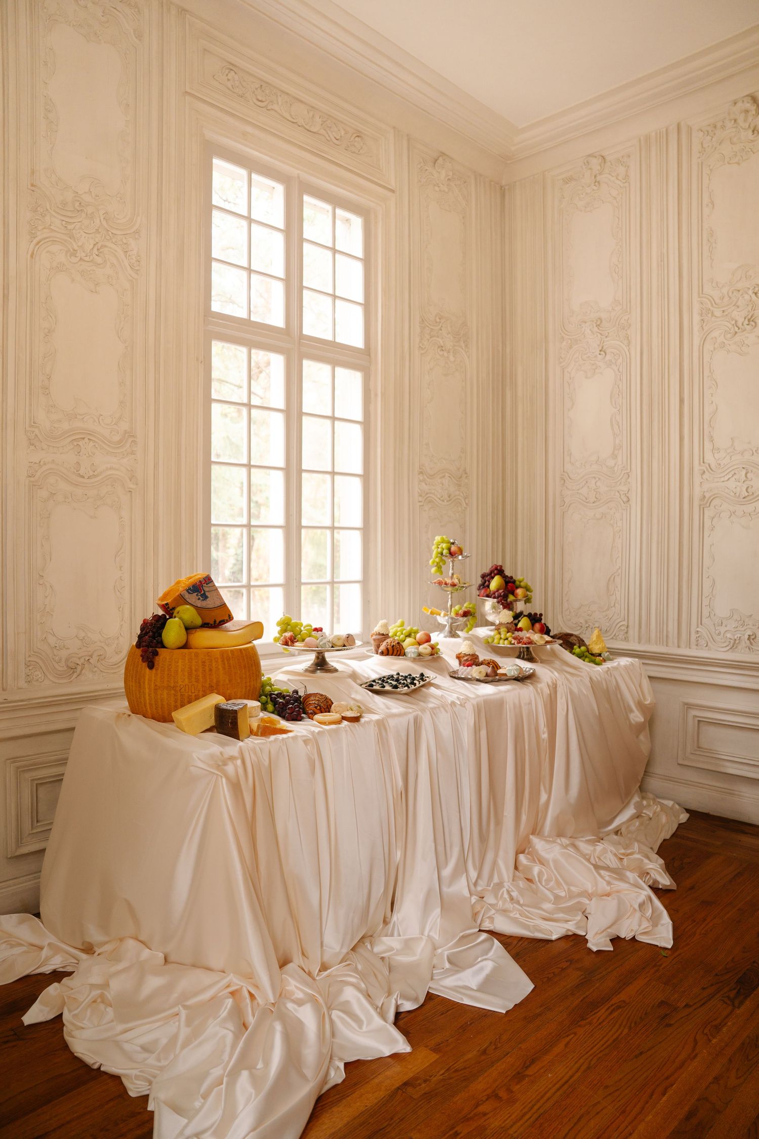 Elegant white room with ornate moldings and long tables draped in white linens.