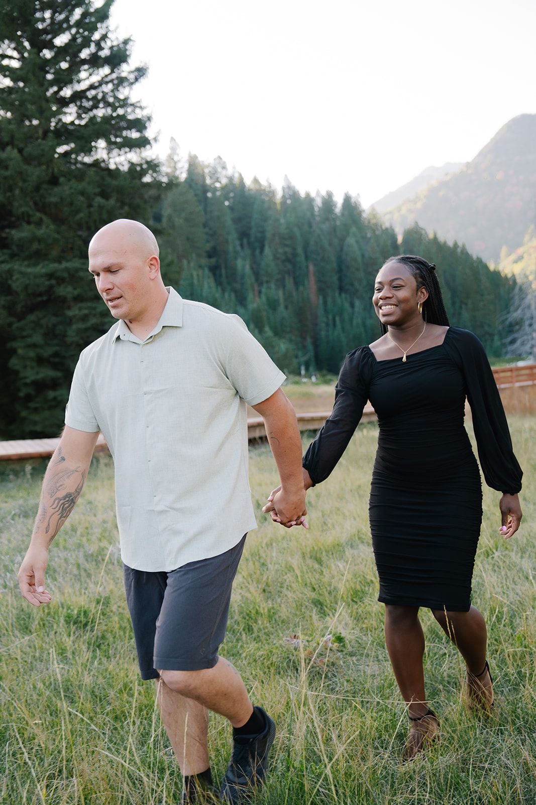 Playful couple dancing and laughing together in mountain meadow.