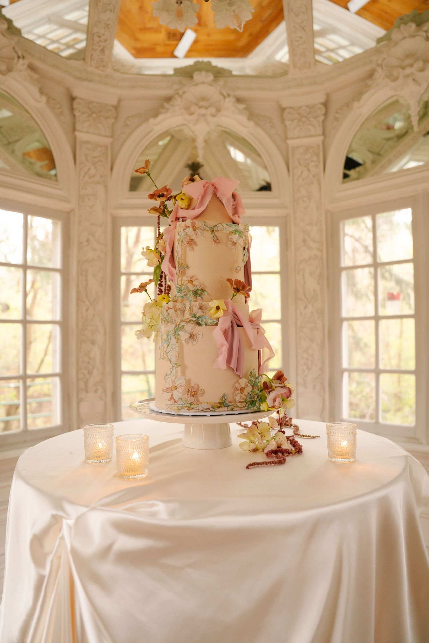 Elegant white room with decorative ceiling, large windows, and wedding cake display.