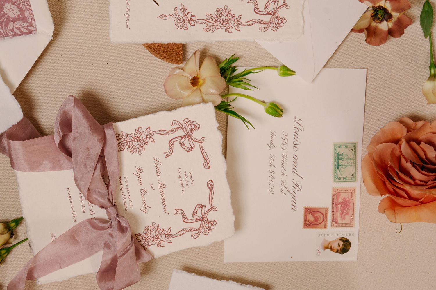 Vintage-style wedding invitations with pink floral designs and postage stamps.