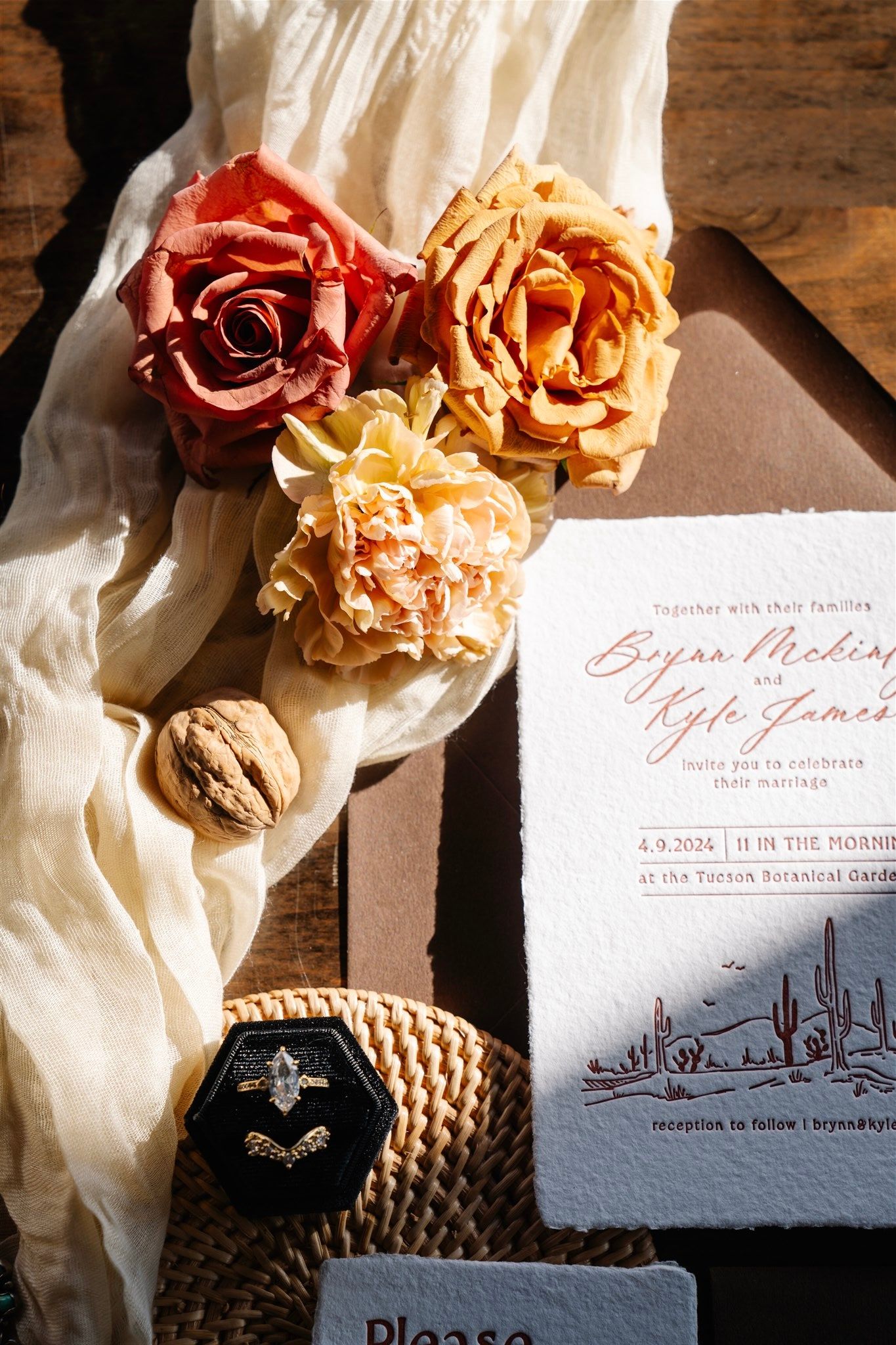 Wedding invitations styled with roses and calligraphy on textured paper.