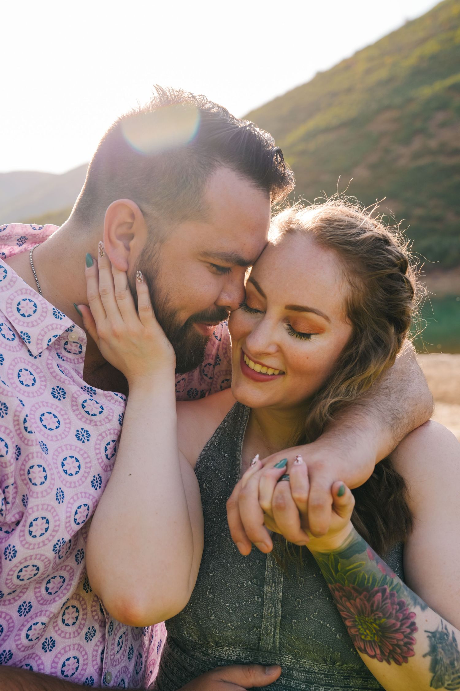 Close-up of a couple sharing a tender moment against a mountain backdrop at sunset.