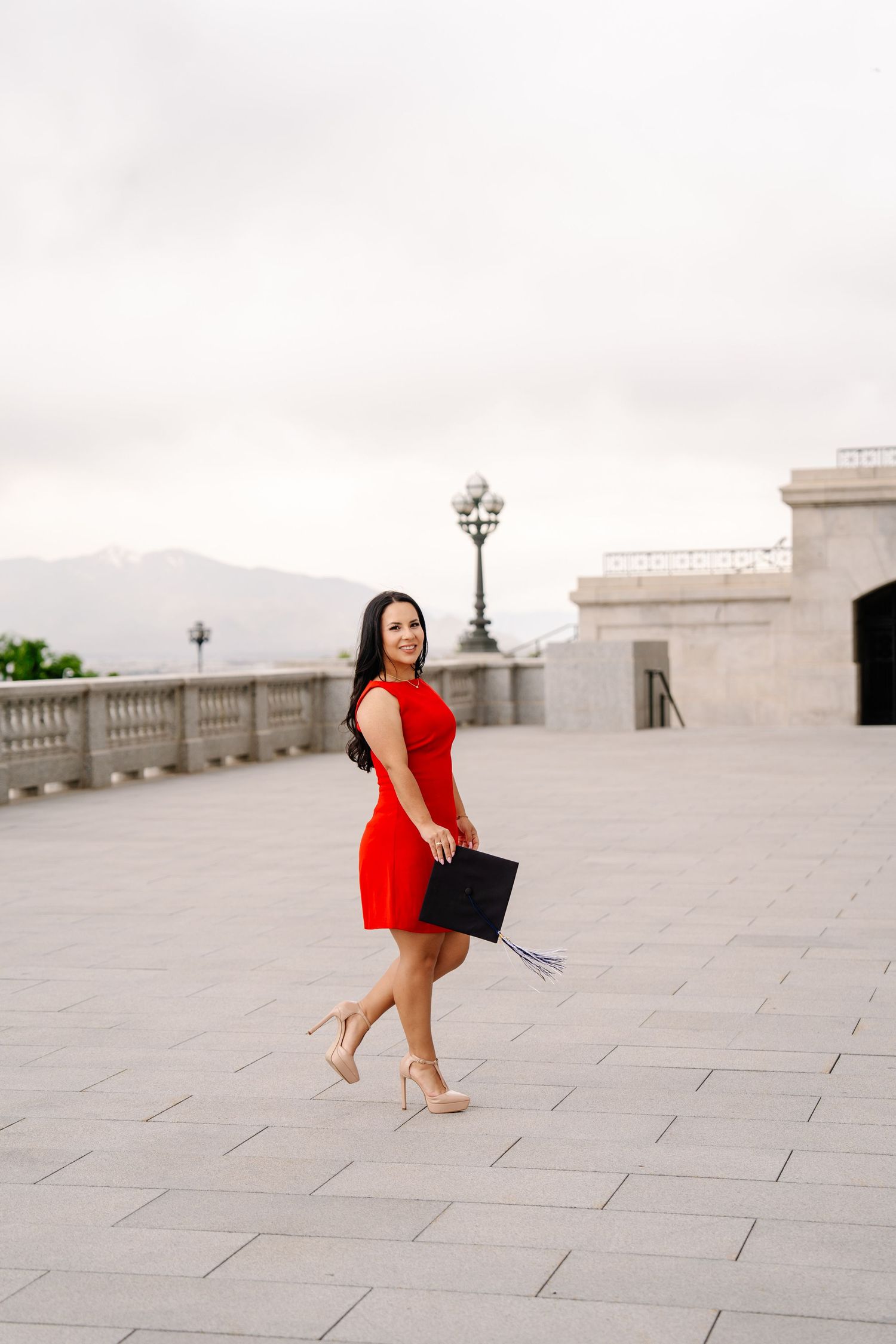 A woman in a vibrant red dress dances gracefully on a light stone terrace.