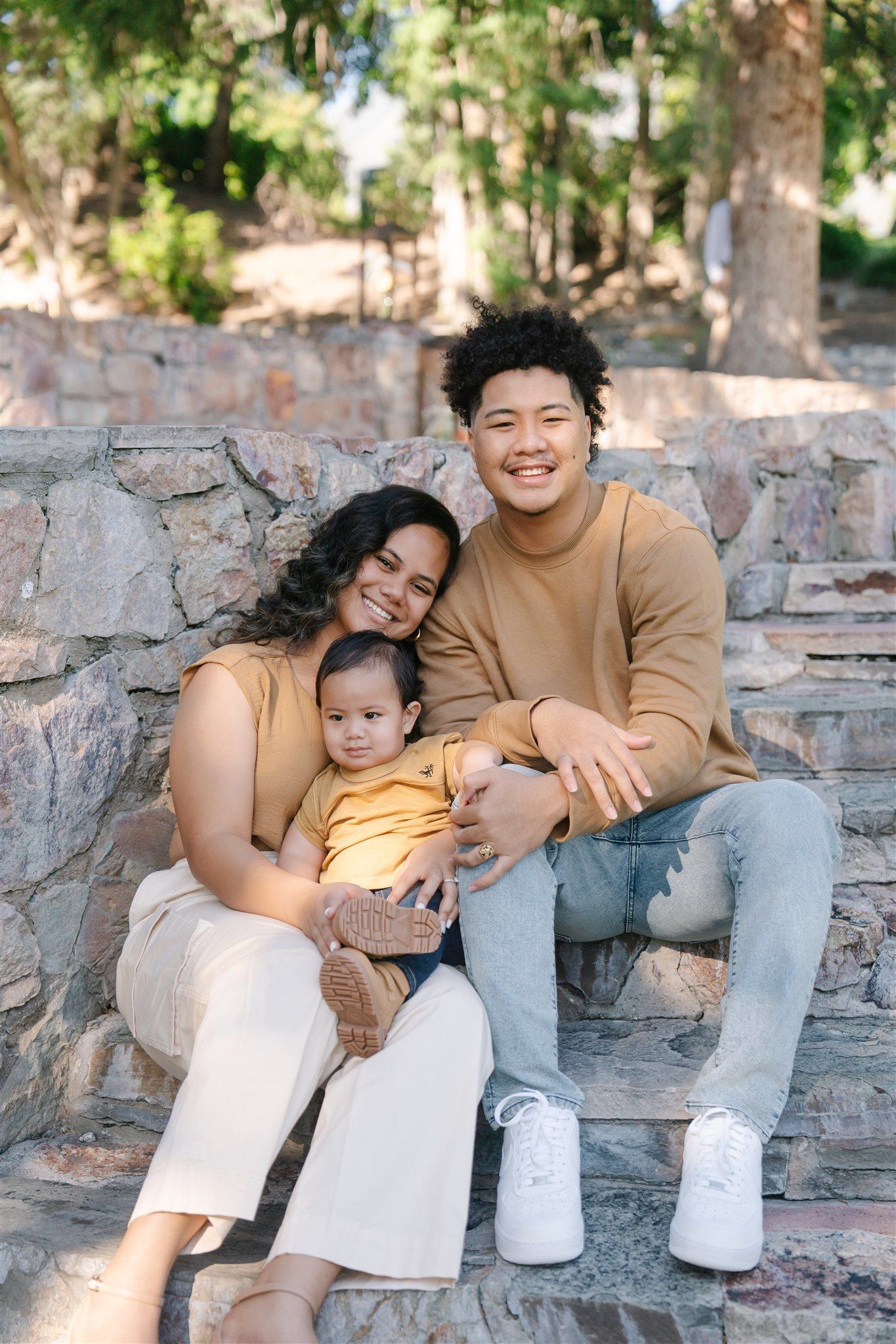 Family sitting on stone steps sharing tender moments together outdoors.