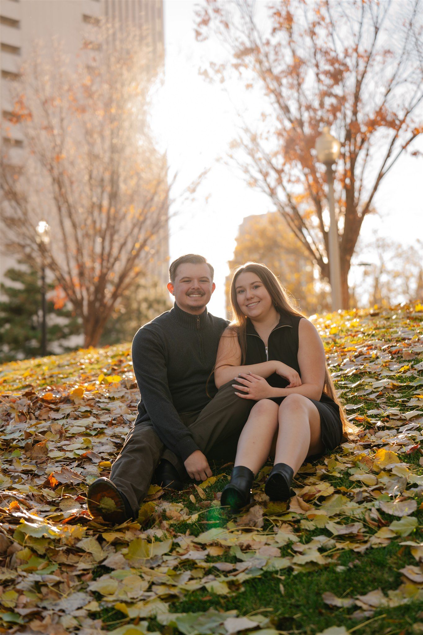 Romantic autumn couple photos with fallen leaves creating a natural golden setting.