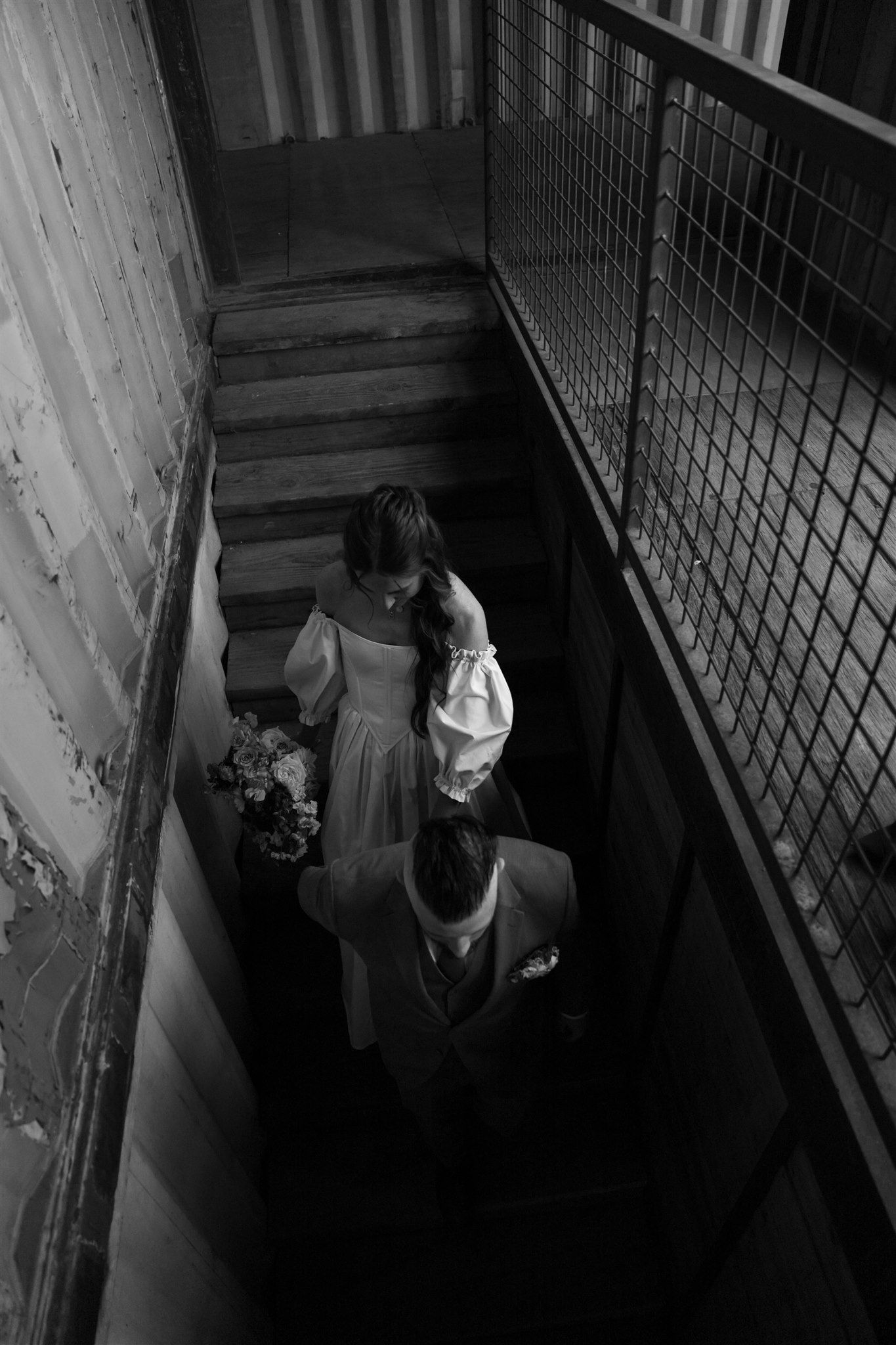 Dark atmospheric wedding photo shoot in an industrial stairwell setting.