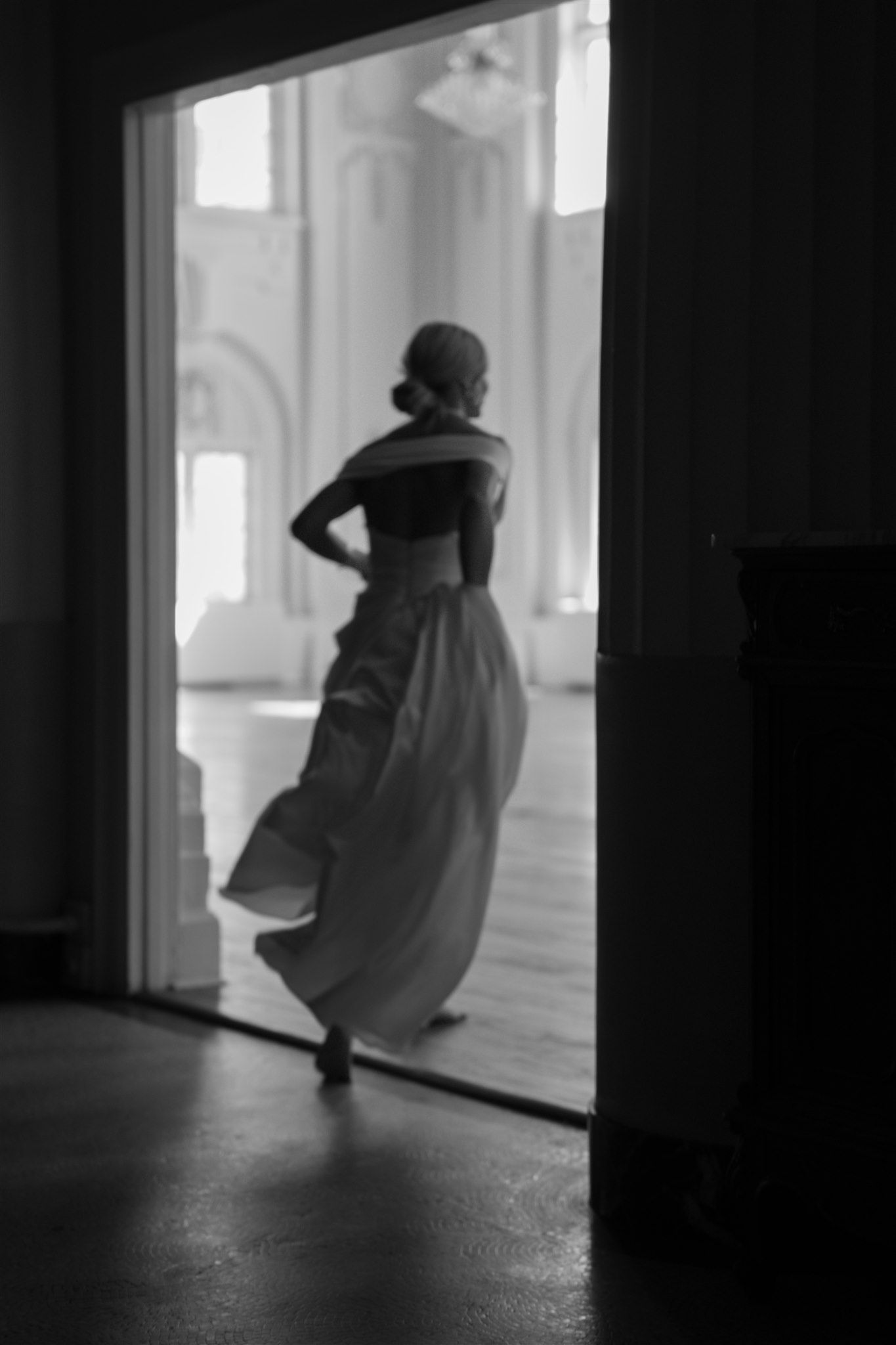 Artistic black and white silhouette of flowing dress in dramatic window light.