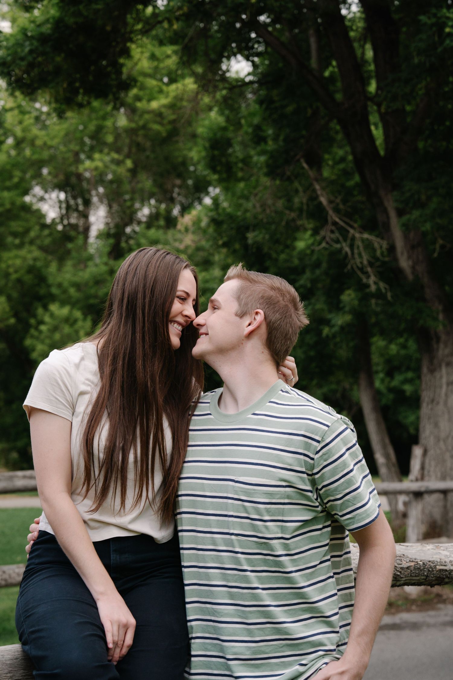A romantic couple shares tender moments while sitting outdoors.
