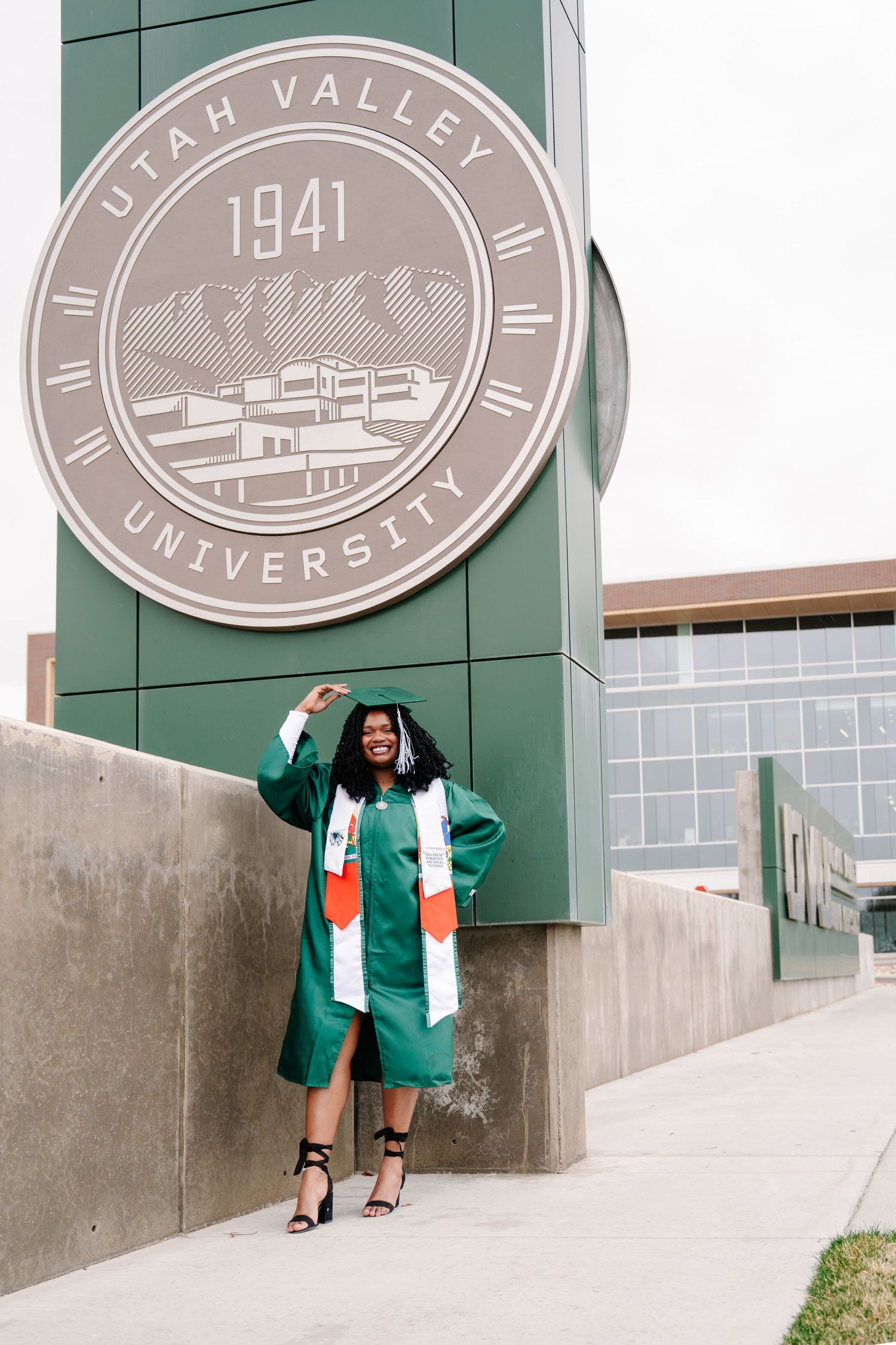Graduation photo series in front of Utah Valley University 1941 building seal.