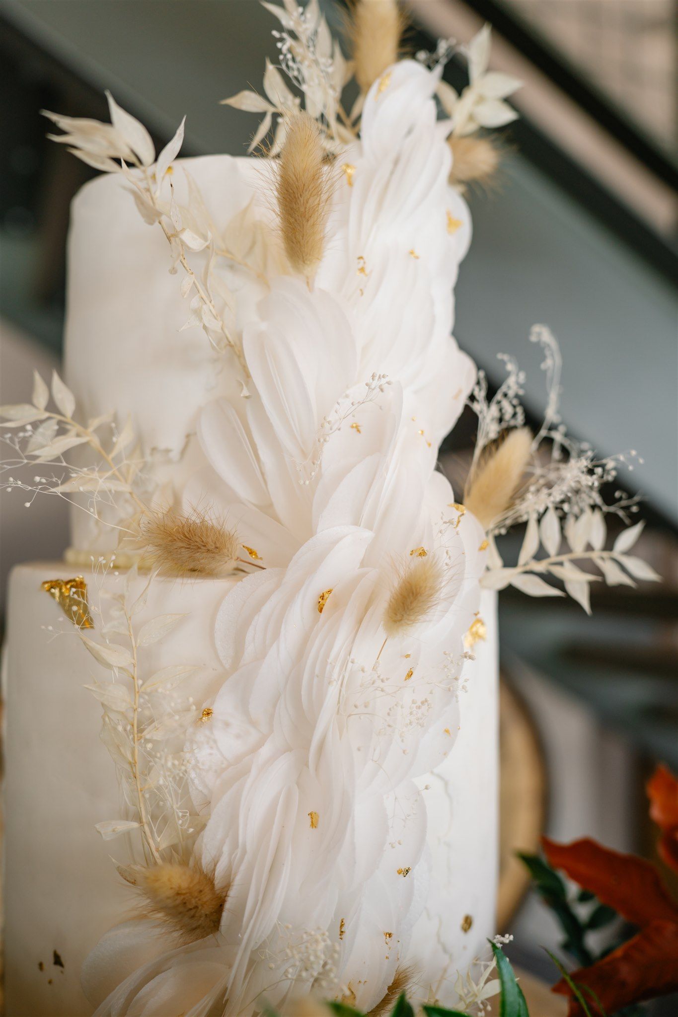 White wedding cake decorated with delicate paper butterflies and gold accents.