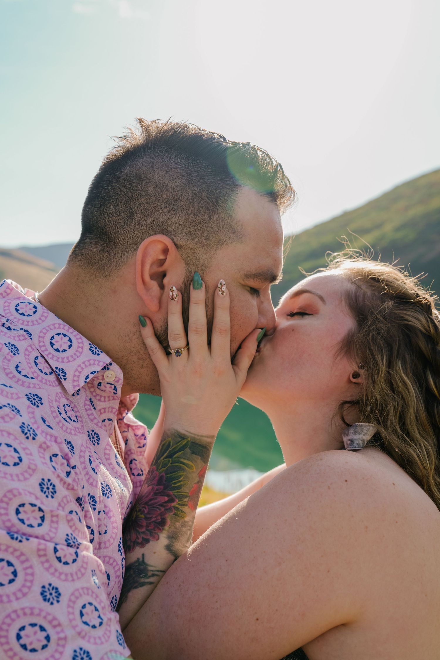 Romantic couple sharing intimate kisses in a scenic outdoor setting during golden hour.