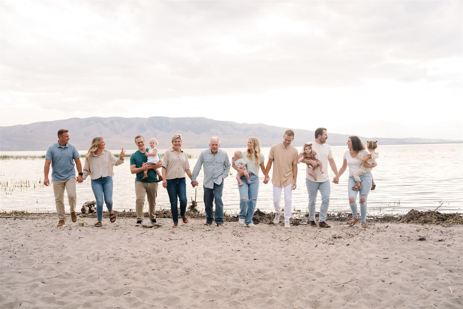 Large group wearing white and blue clothing poses together on a sunny beach.