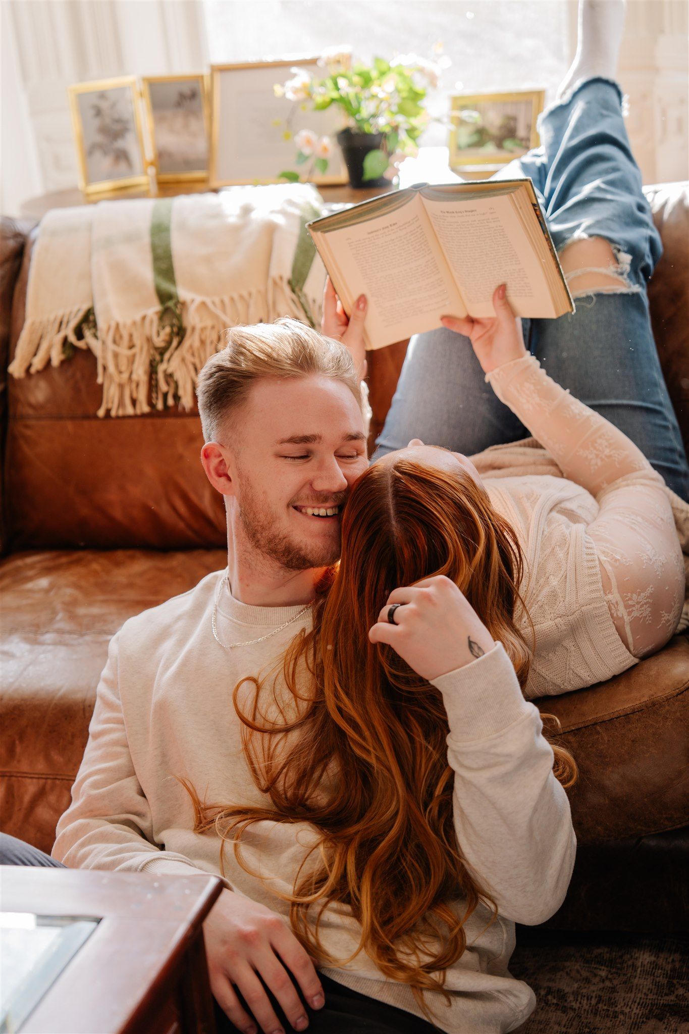 Couple cuddling and laughing together on a comfortable couch with throw pillows.
