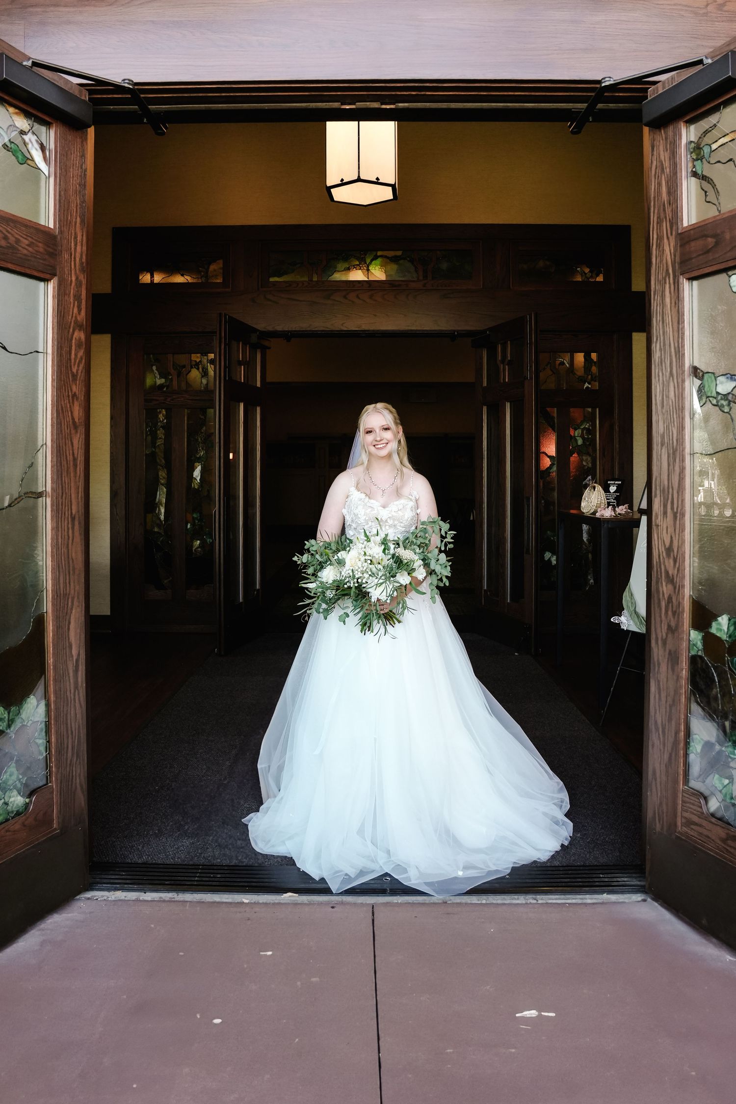 White wedding gown displayed in a rustic wooden doorway entrance.