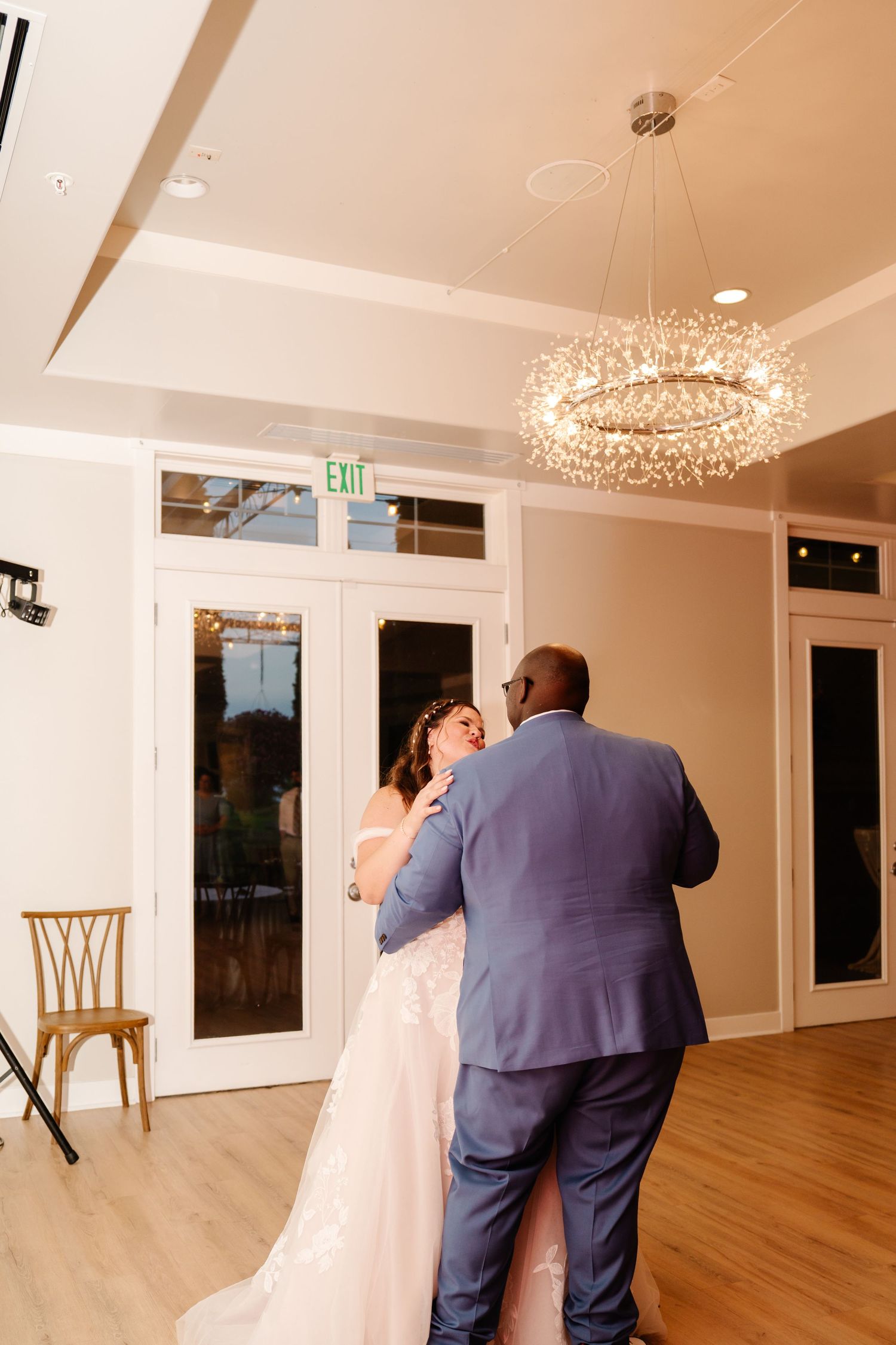 Couple sharing their first dance under an elegant crystal chandelier in a reception hall.