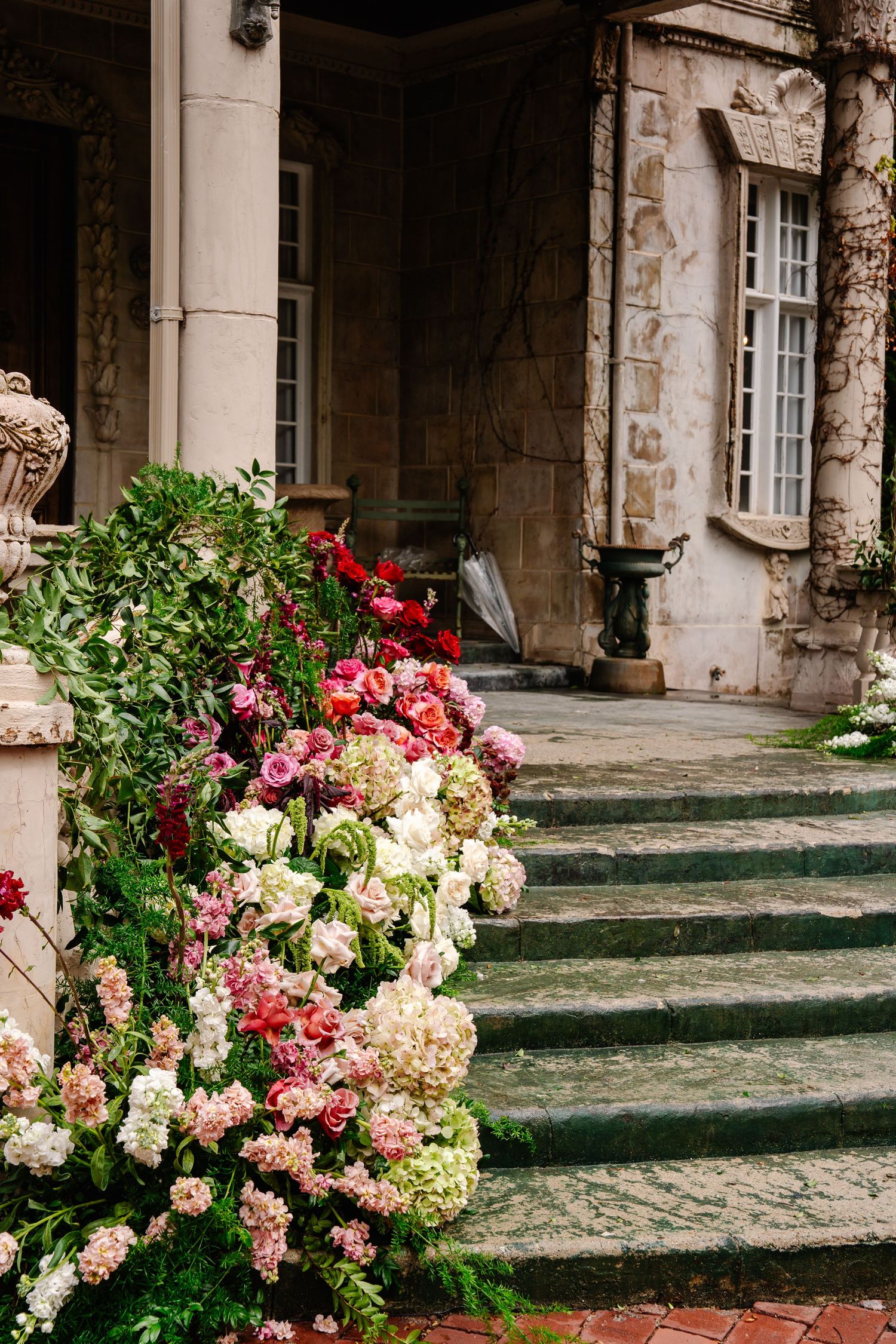Stone colonnade decorated with lush floral arrangements in pink, red and white blooms.