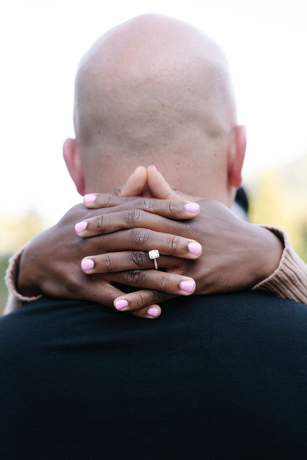 Close-up of hands tenderly embracing, showing wedding ring and pink nail polish.