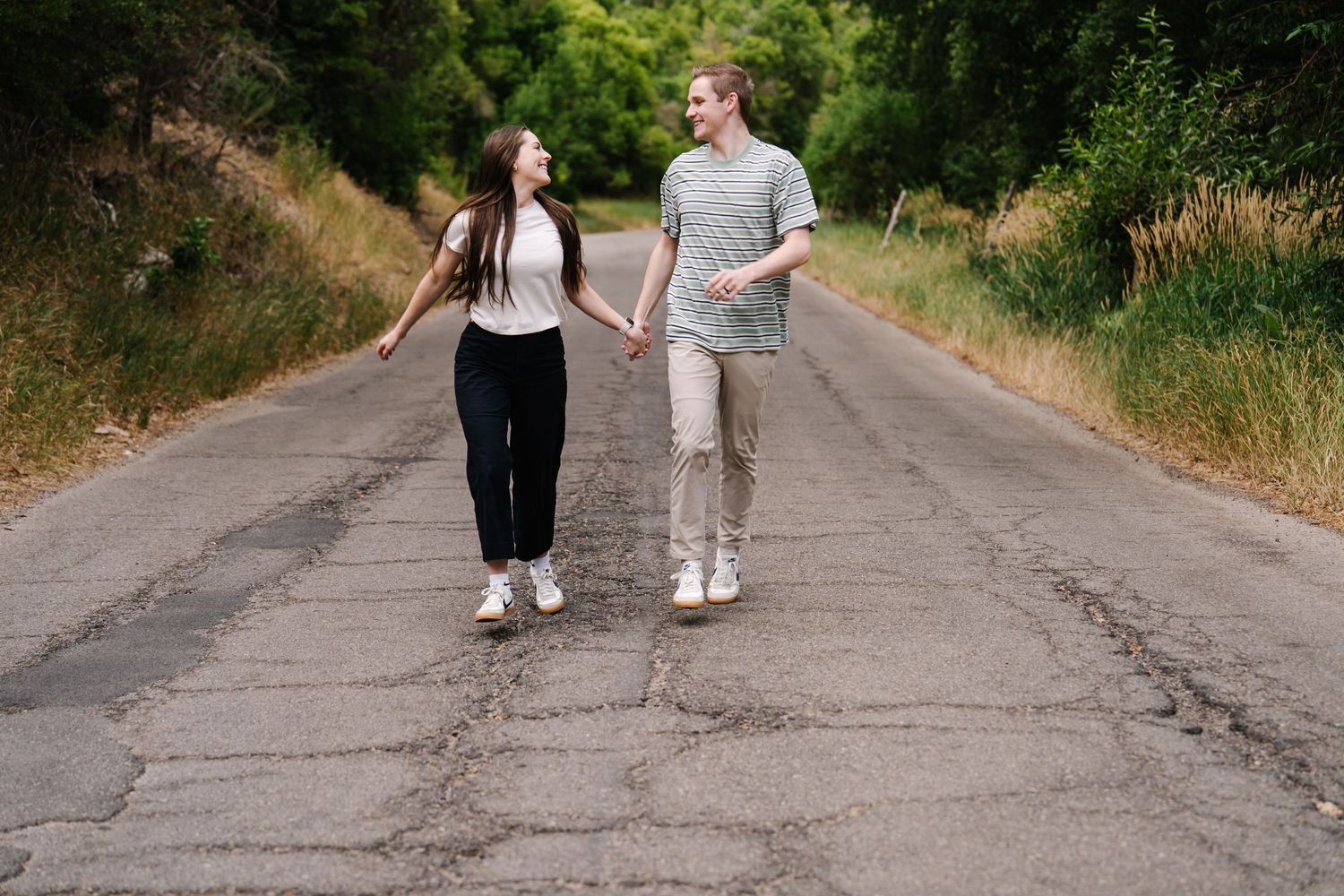 Two people walking hand in hand down a peaceful country road.