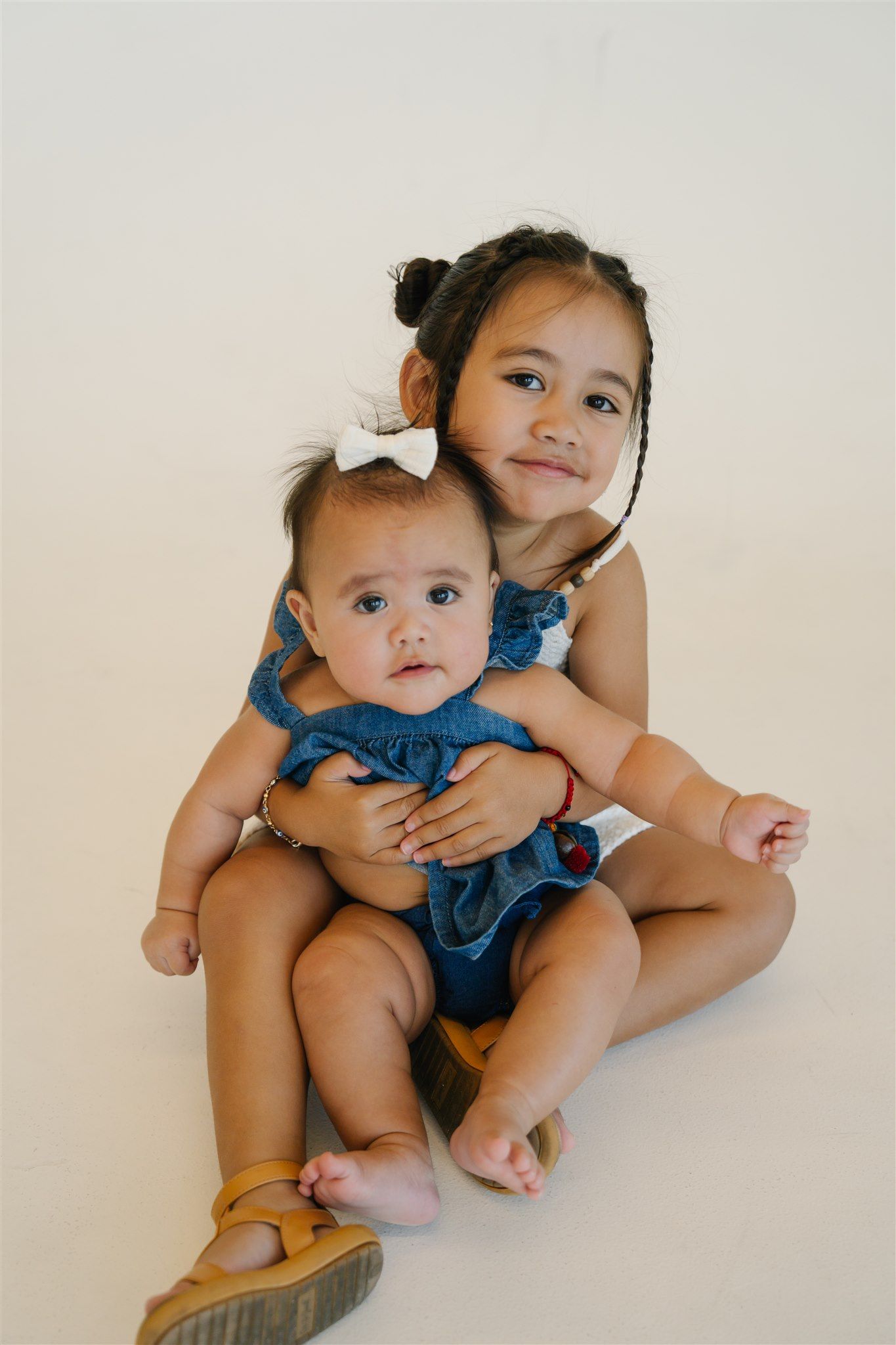 Baby in blue outfit sitting on floor during intimate portrait session.