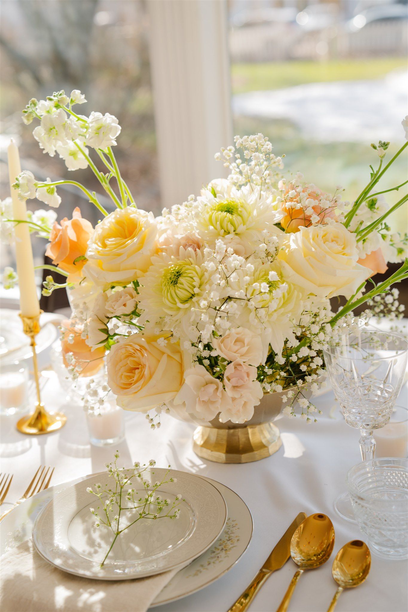 Elegant table setting with peach and cream floral centerpieces and gold accents.