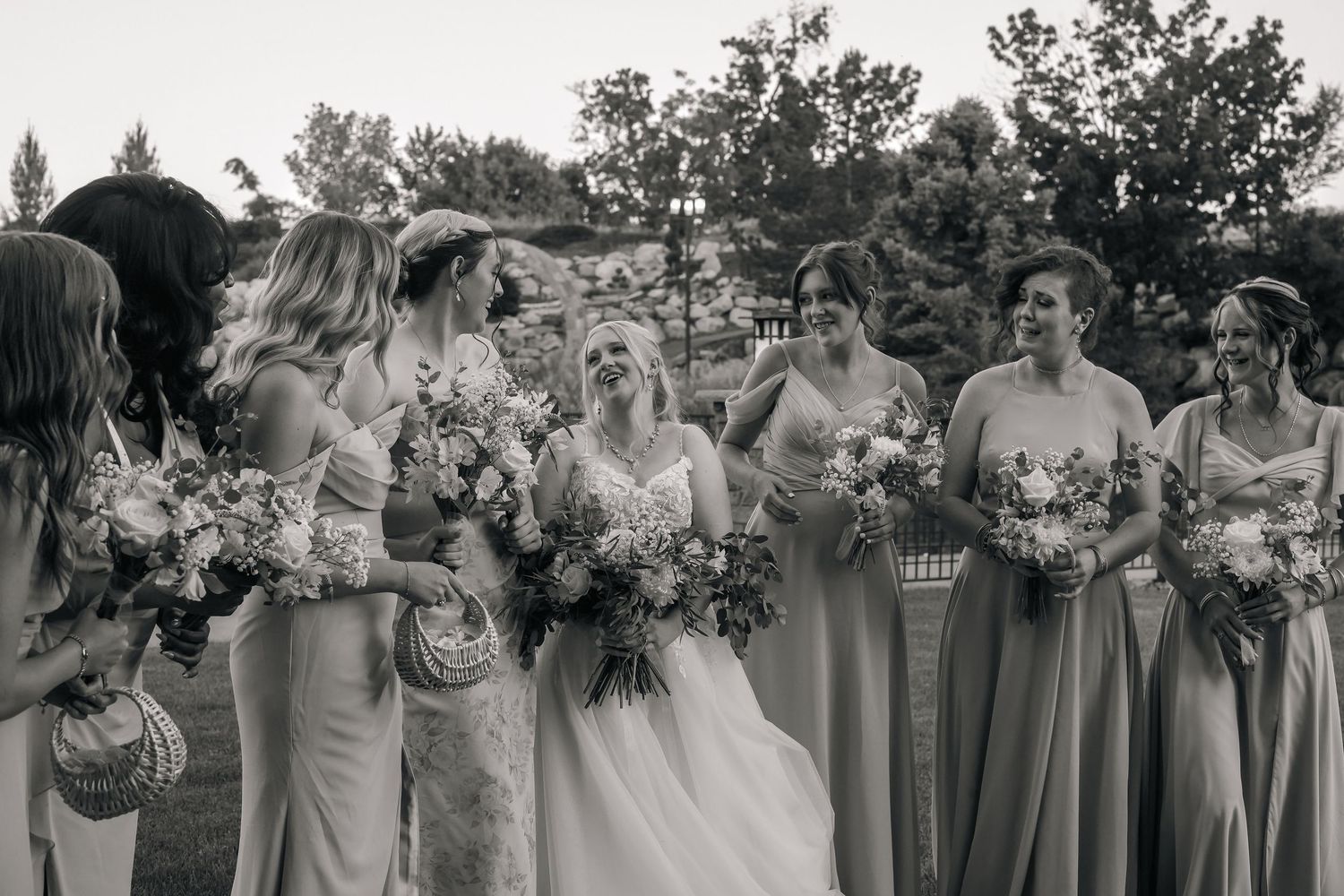 Wedding party holding floral bouquets poses together for group photos.