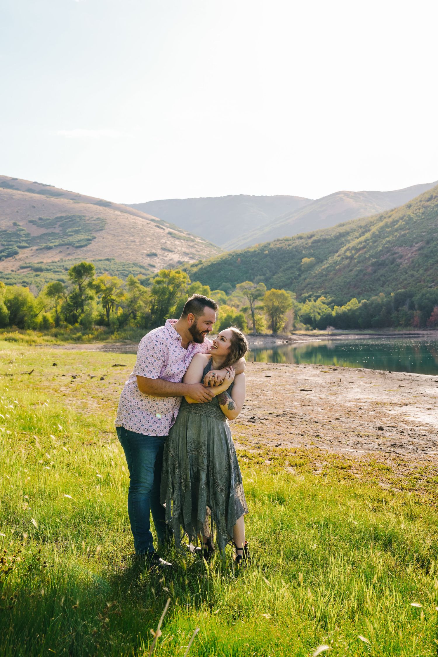 Couple sharing an intimate moment in a scenic mountain valley with a lake view.