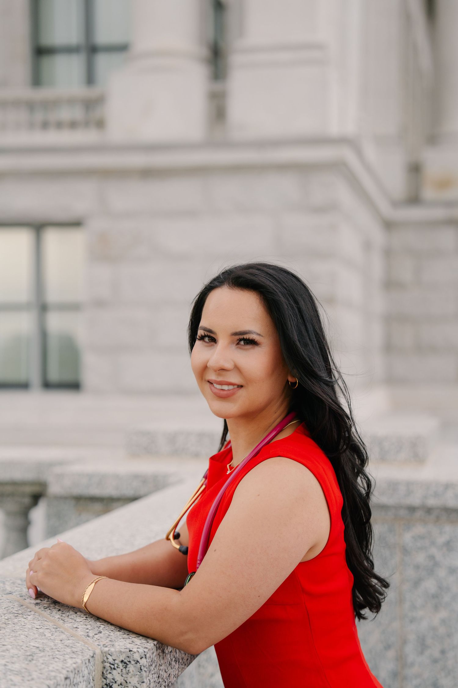 Red sleeveless dress worn against classic stone architecture.