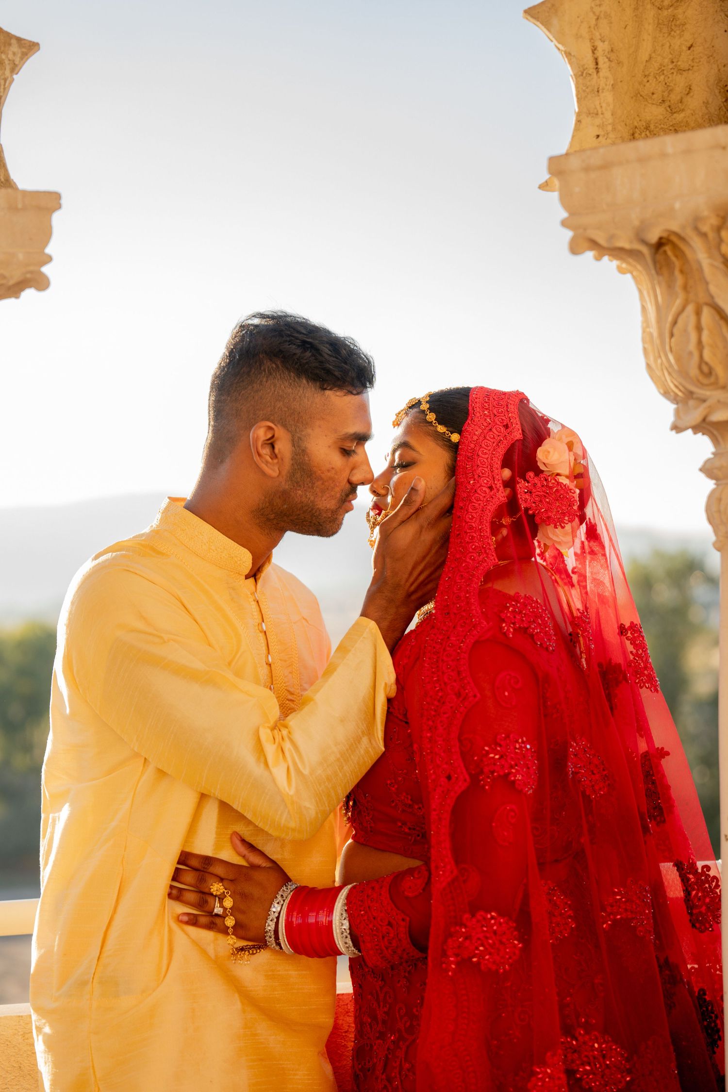 A traditional Indian wedding couple shares an intimate moment in golden light.