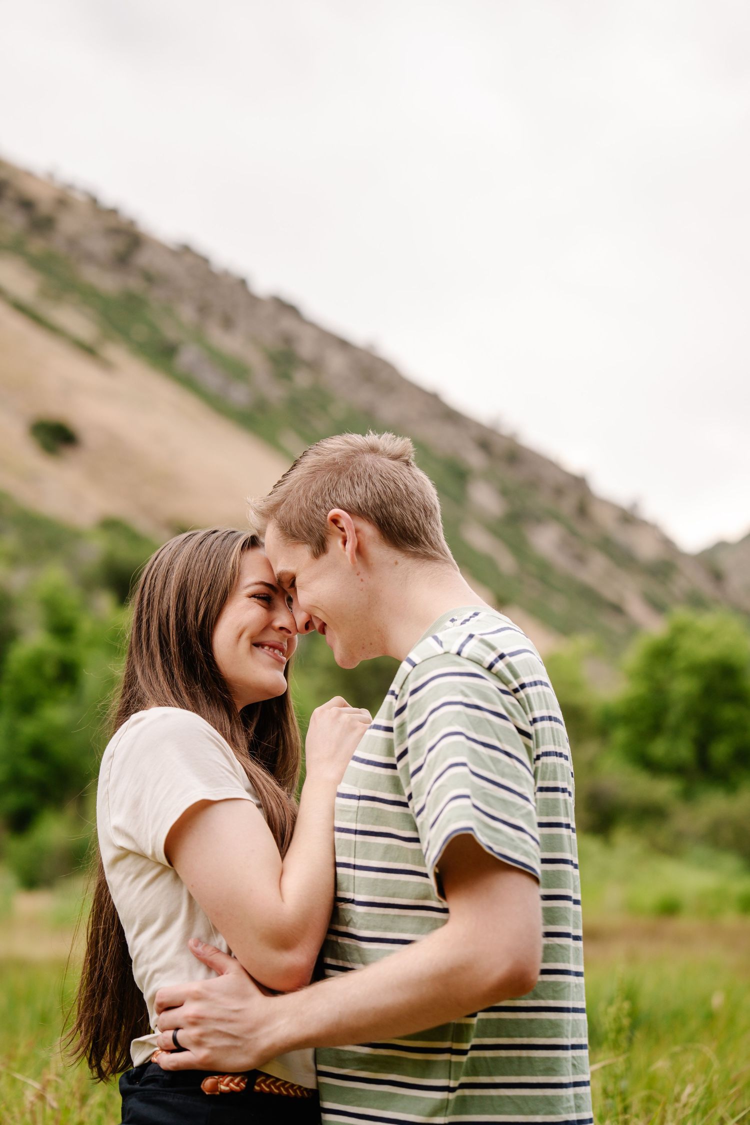 Romantic moment captured in outdoor setting with mountains in background.