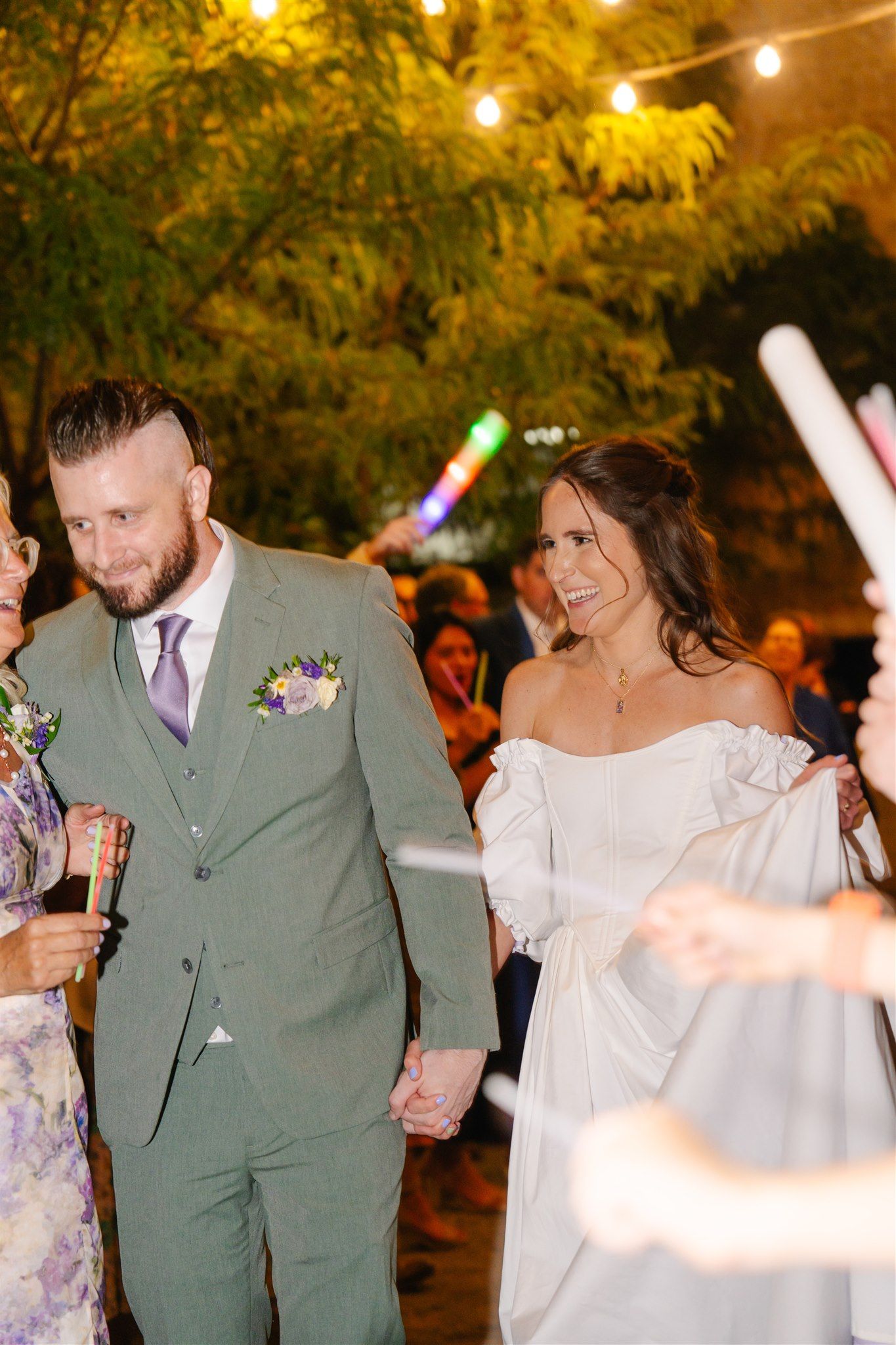 Wedding couple dancing at night under string lights at outdoor reception.