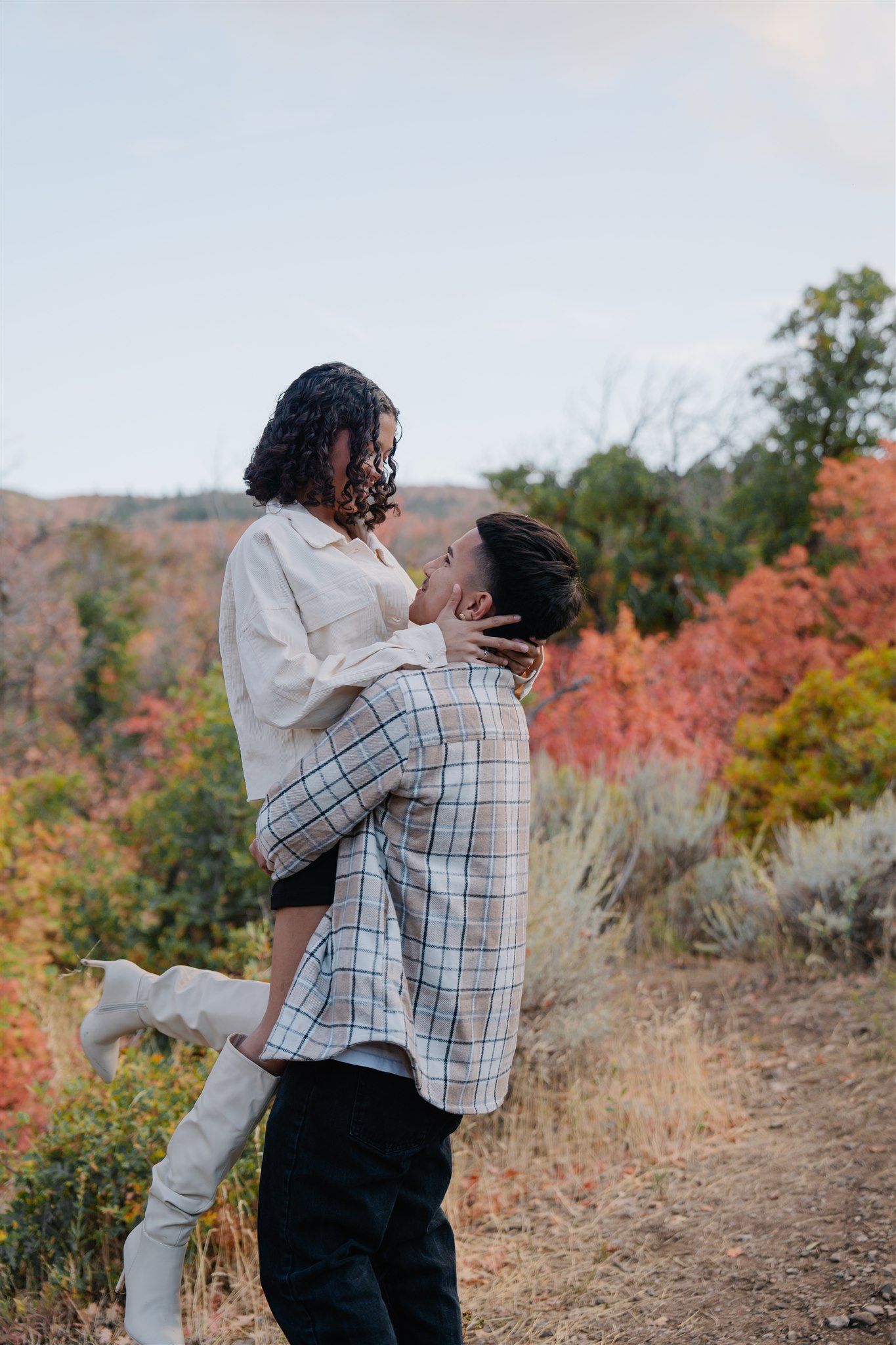 Romantic autumn engagement photoshoot in a field with warm fall colors and natural scenery.