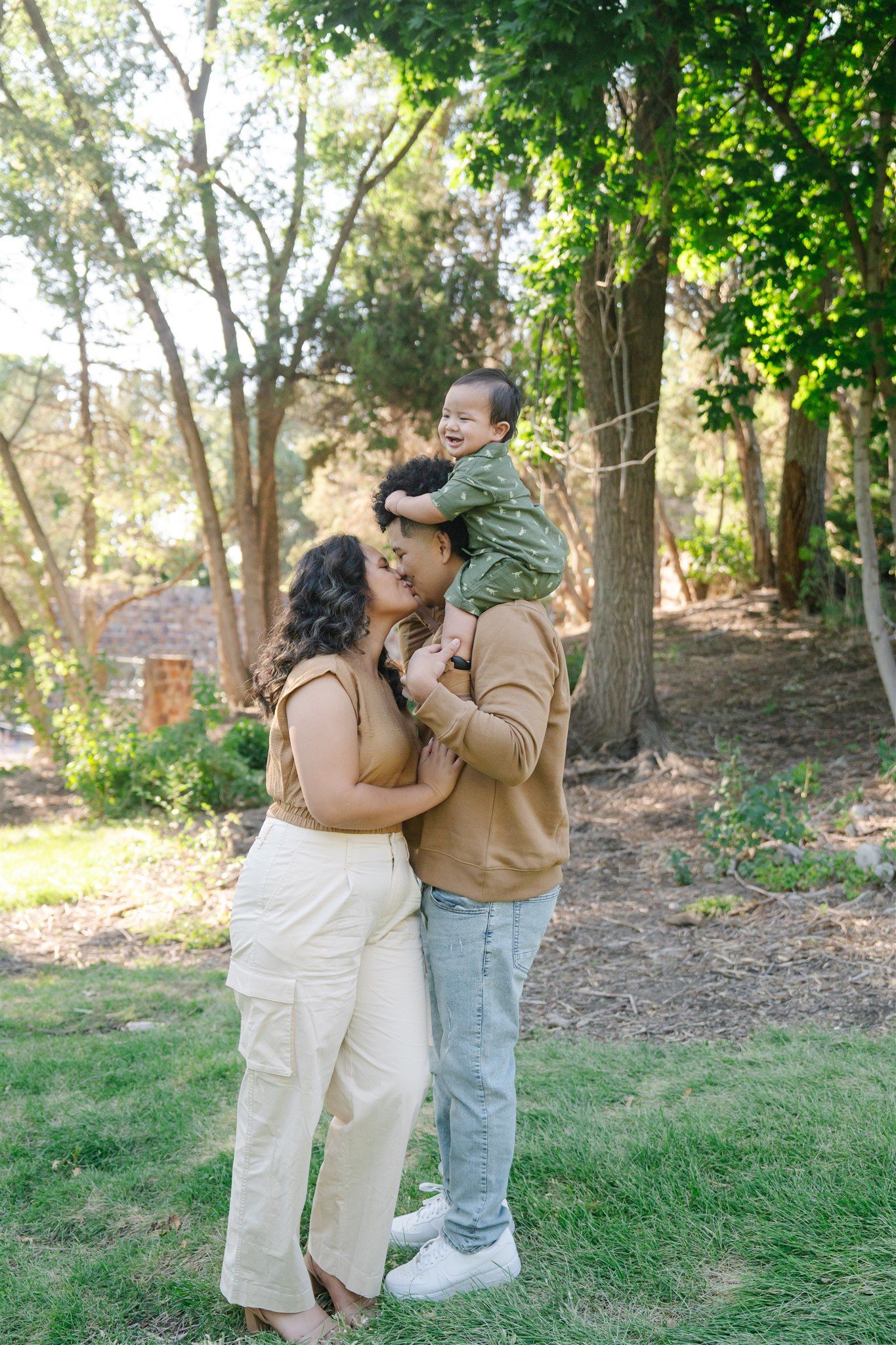A couple shares a tender moment together in a sunlit outdoor garden setting.