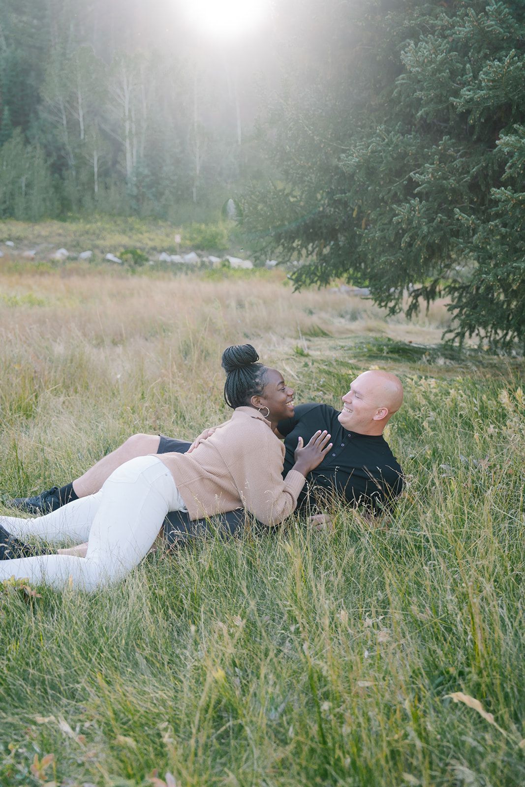 Couple lying together in tall grass during misty afternoon.