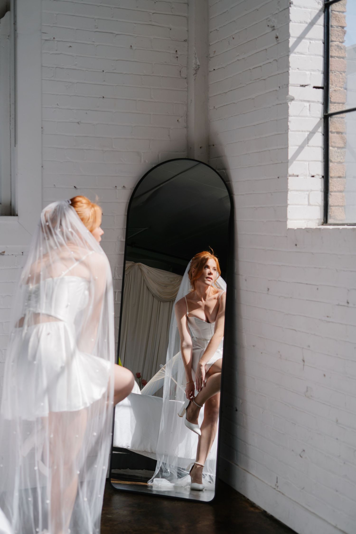 Ethereal bridal boudoir session with flowing white fabric in a bright studio space.