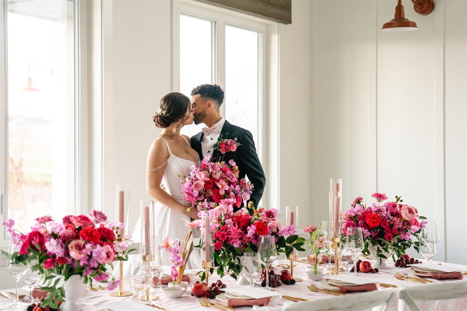 Bride and groom share a kiss in front of bright window with pink florals — captured by Salt Lake City wedding photographer