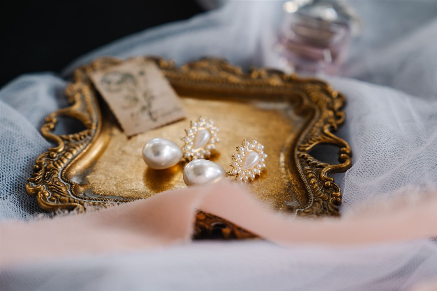 Delicate pearl and lace wedding accessories arranged on vintage fabric.