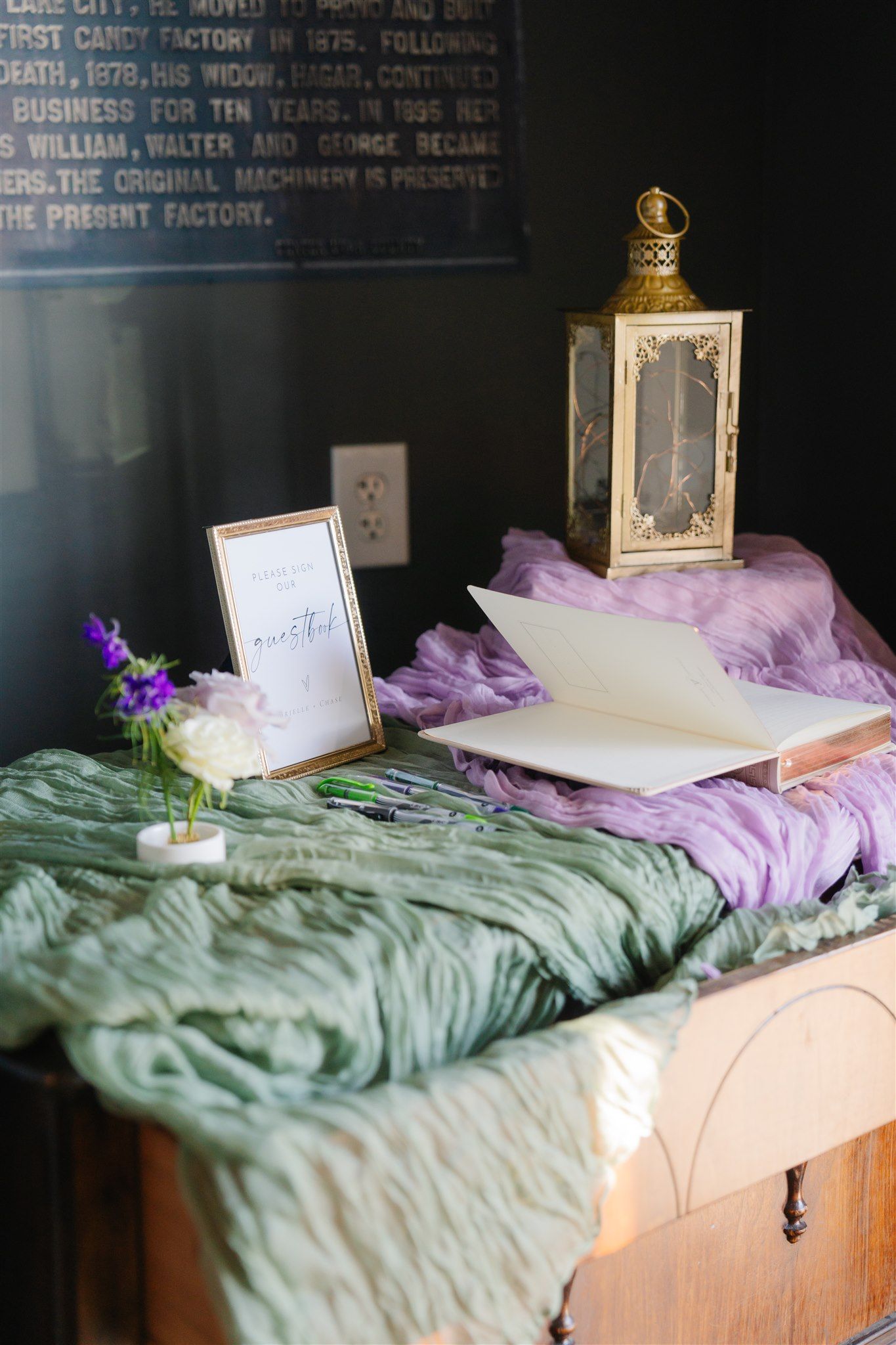 Wedding decor display with purple tulle and gold lanterns on white table.