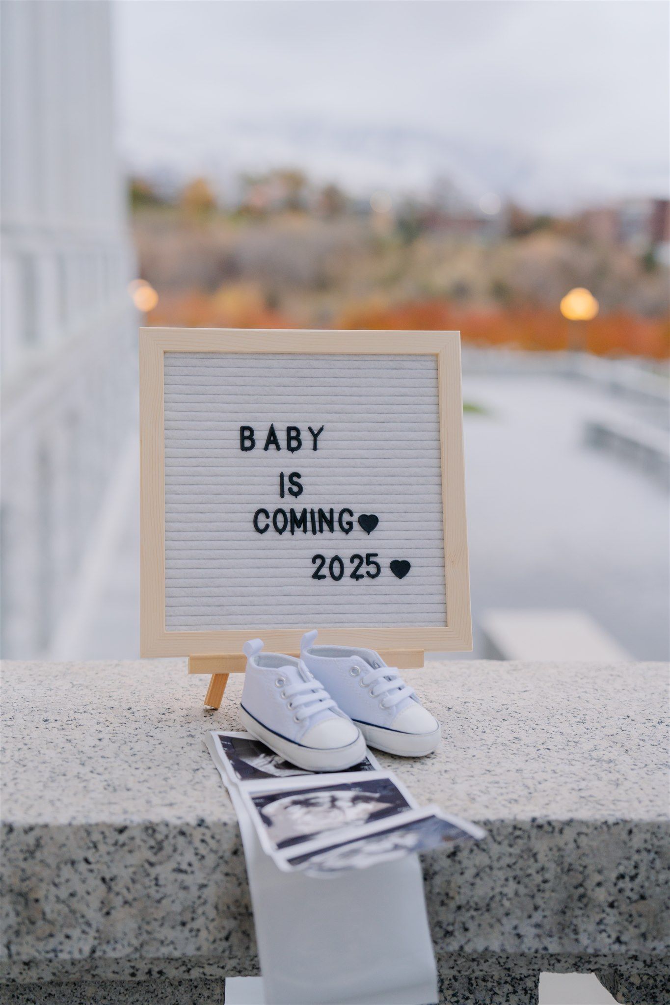 Baby shoes and letter board announcing new baby coming in 2023.