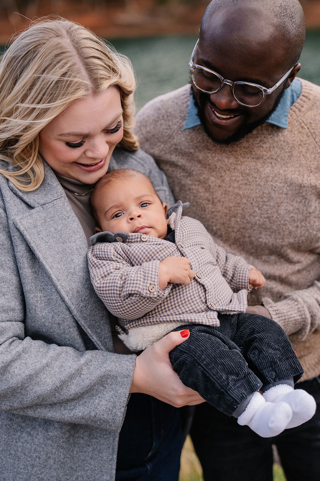 A family shares an intimate moment together outdoors while holding their baby.