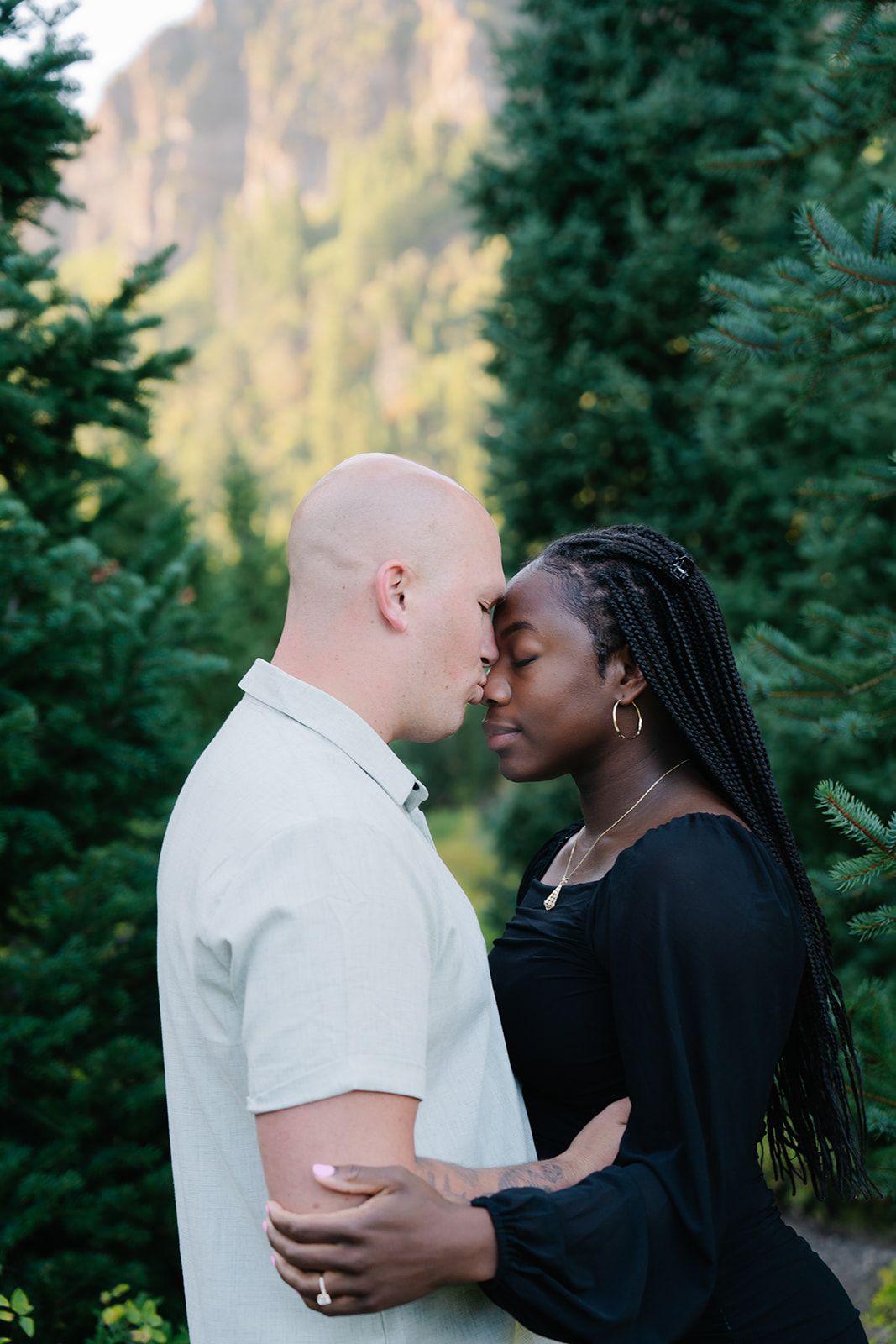 Intimate couple portraits captured against a backdrop of mountain scenery and evergreen trees.