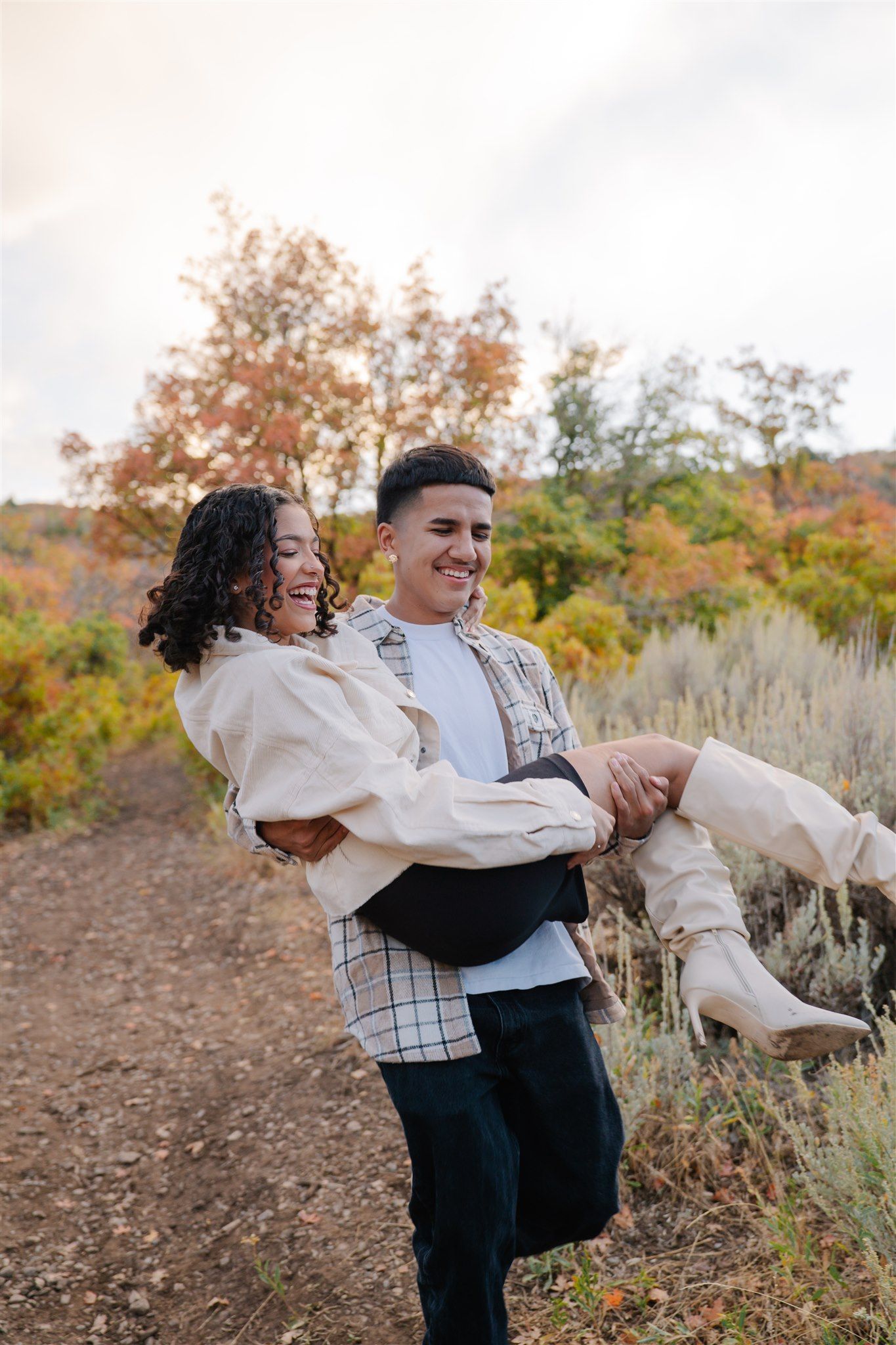 A couple embraces and spins joyfully in a field during autumn.