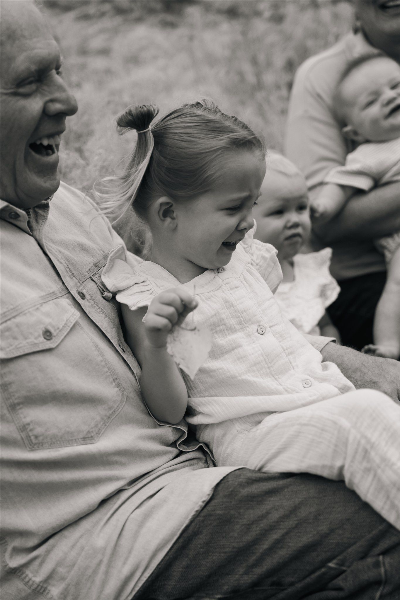 Black and white photo showing joyful laughter and smiles in a candid family moment.